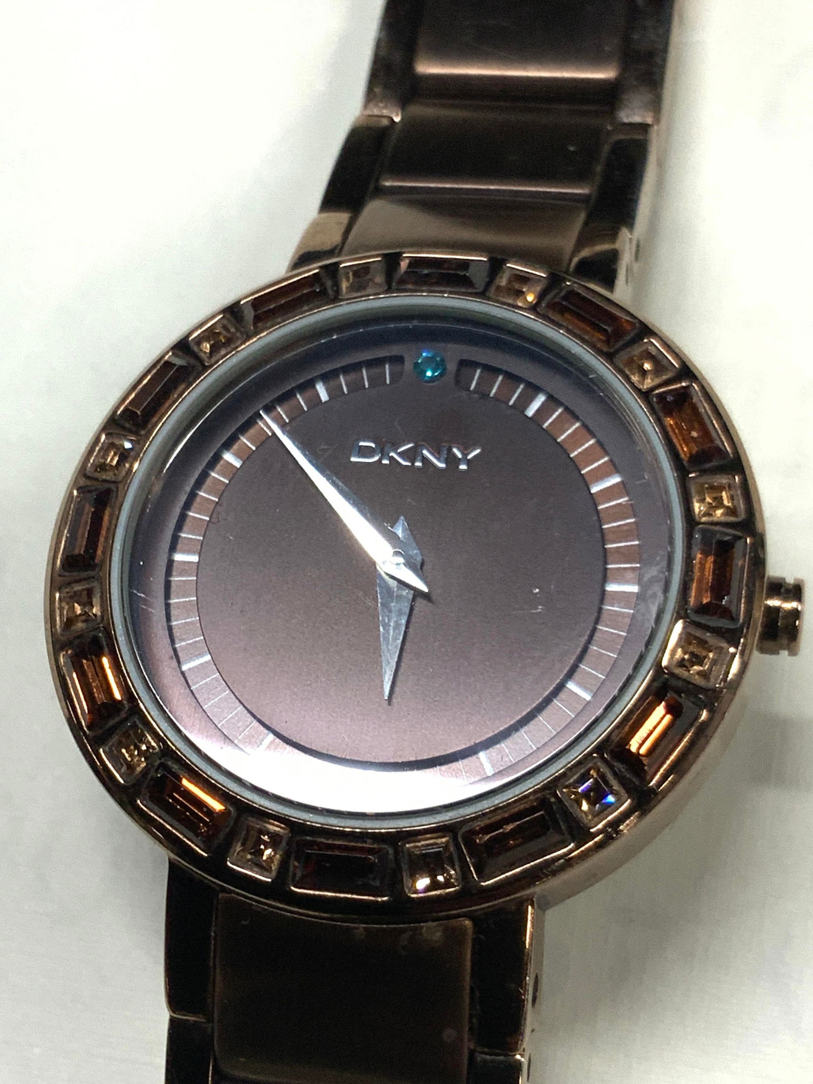 DKNY Modernist Style Metal Wrist Watch: Marked on band and watch face, DKNY. Metal sectioned wrist band and crystal halo watch face, all in a chocolate brown tone with modernist style watch face. Stainless steel backing Approx,7 inches long