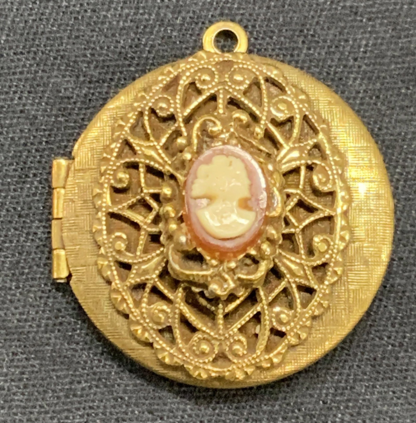Vntg Gold Tn Cameo Locket: Vintage locket in gold toned with raised ornate designs and white cameo on front. Approx 1.25 x 1.25 inches. Moderate repairing to cameo and wearing to metal Gold toned jewelry, locket pendant, pendan