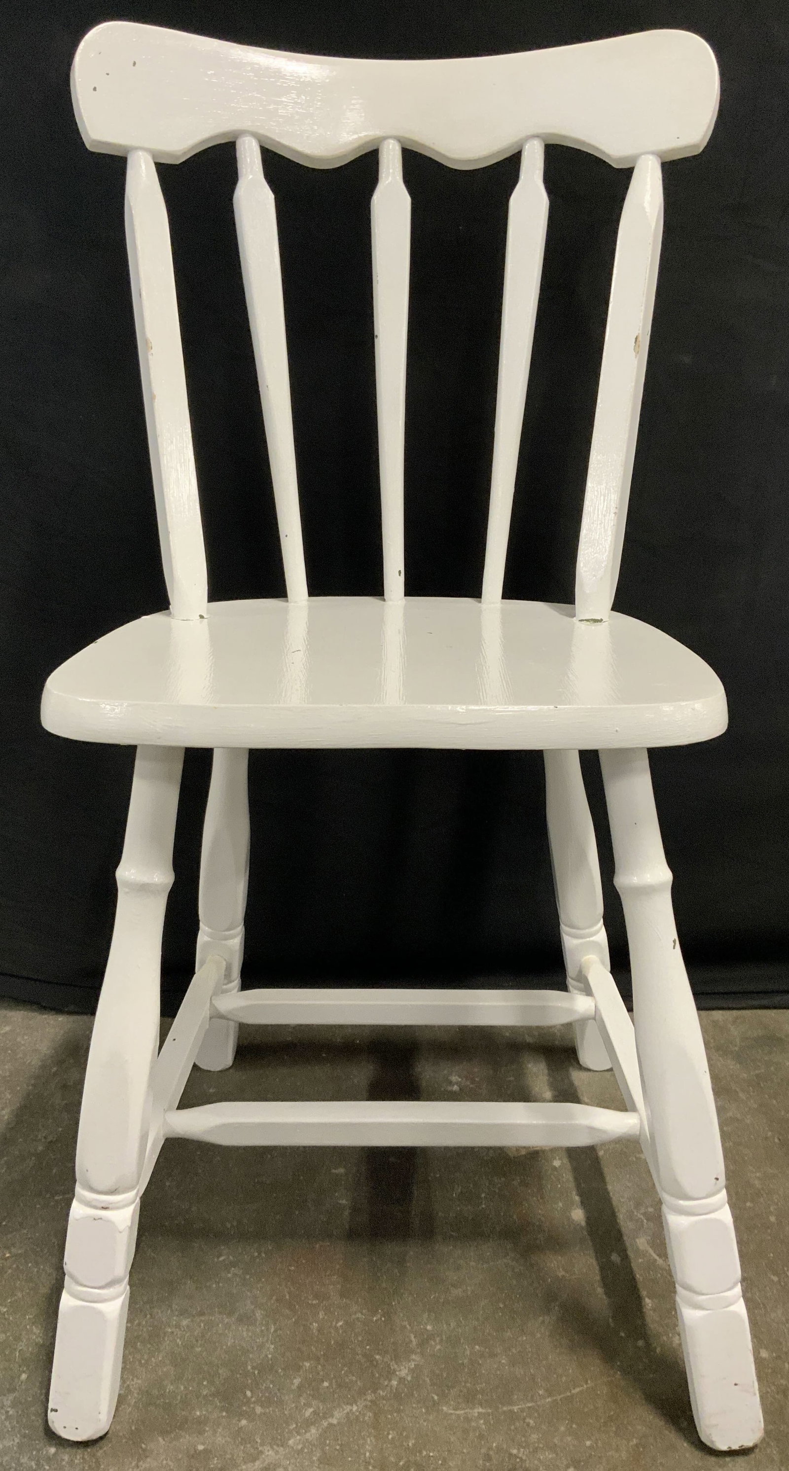 Vintage Wooden Spindle Back Chair White: Chair is white toned and wooden. Piece has spindle backrest. Chair has 4 carved wooden legs with box stretcher in between. Chair appears to be vintage. Chair measures approx 33 inches tall 16 inches w