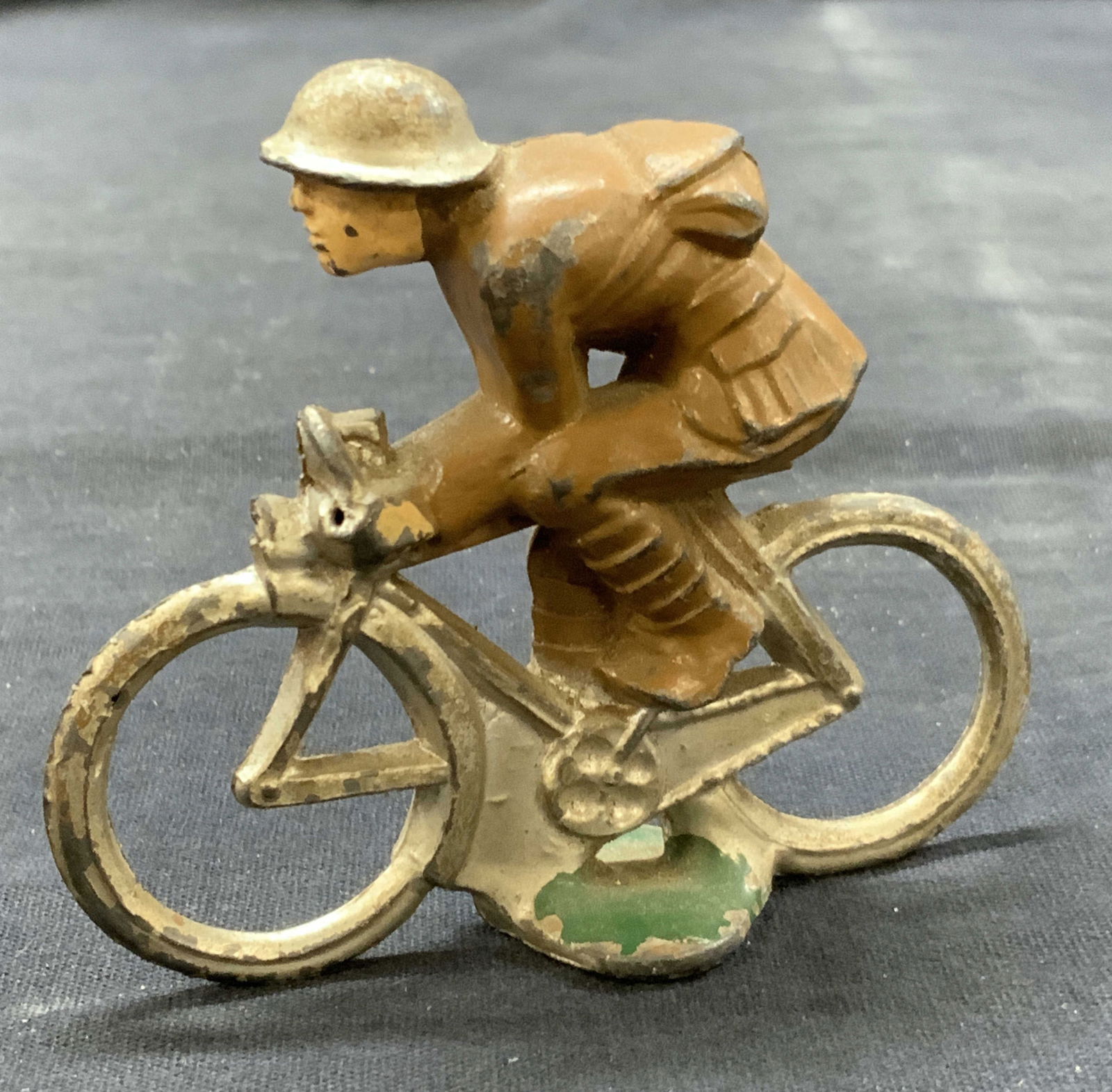 Vntg Painted Tin Solider Toy: Vintage painted tin soldier toy solider depicting a solider on a pedal bike. Approx 3 x 3 inches. Evident wearing and losses to paint on figure. Vintage toys, soldier toys. Tin toys, solider accessori