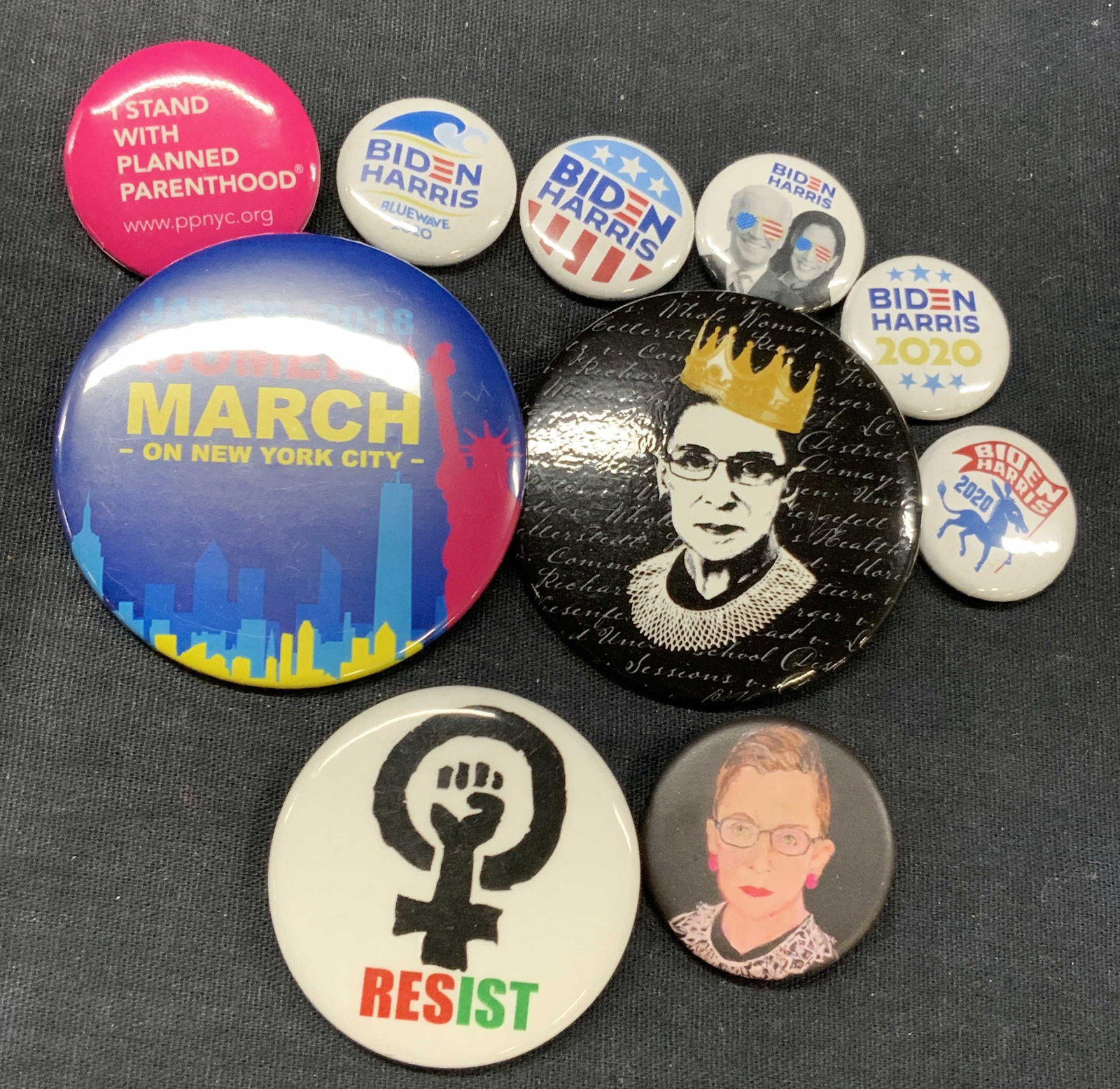 Lot 10 Political & Presidential Campaign Pins: Lot of 10 pin. 2 depicting Ruth Bader Ginsburg. 1 featuring the rise up fist within a female symbol with the word Resist. 1 womens March 2018 pin, planned parenthood pin and 5 Biden Harris 2020, campa