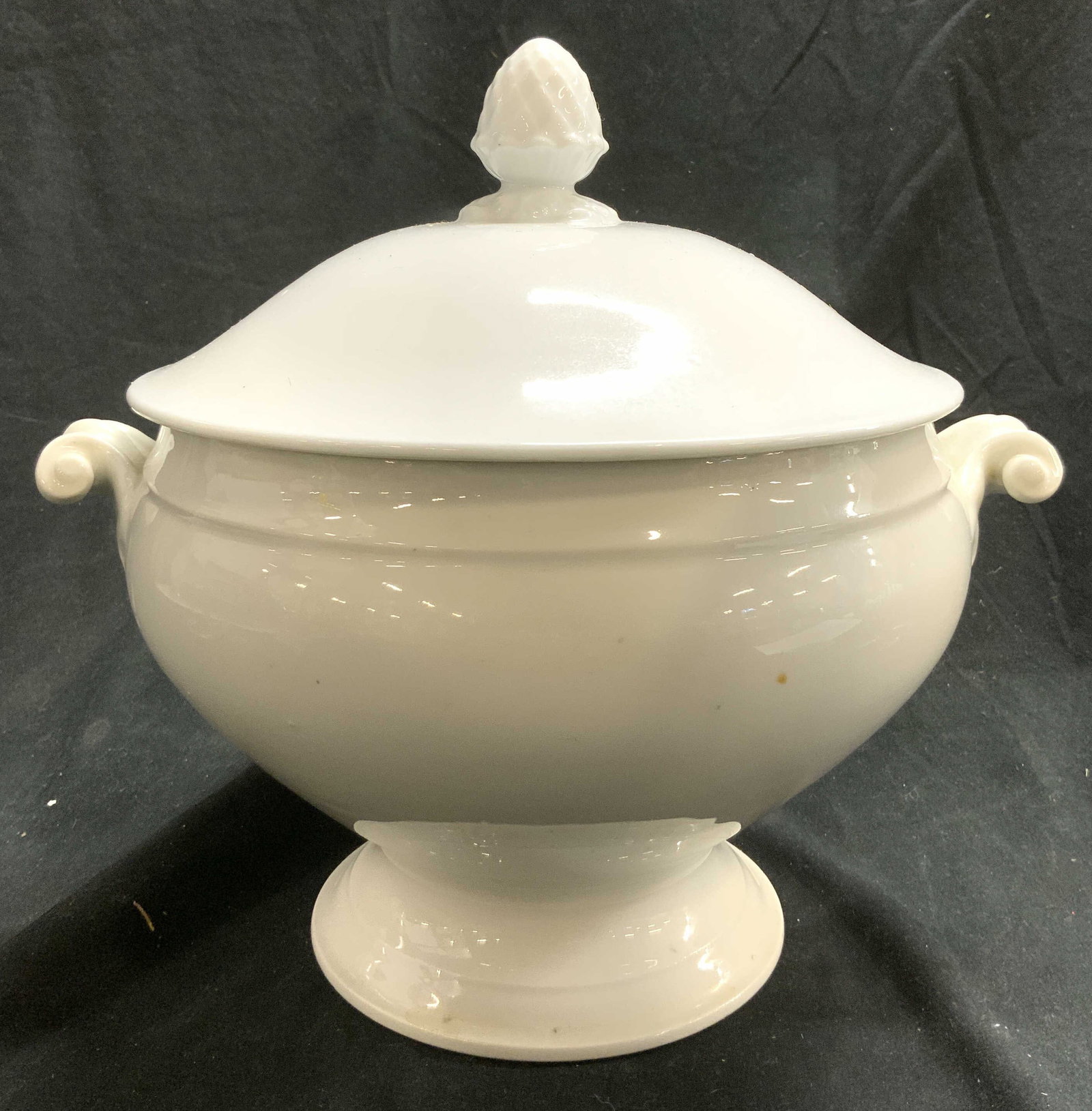 Vintage Lidded Porcelain Tureen W Handles White: Tureen is white toned and porcelain. Piece appears to be vintage. Tureen includes lid. Lid has artichoke finial on top. Sides have curled handles. Tureen measures approximately 10 inches tall 11 inche
