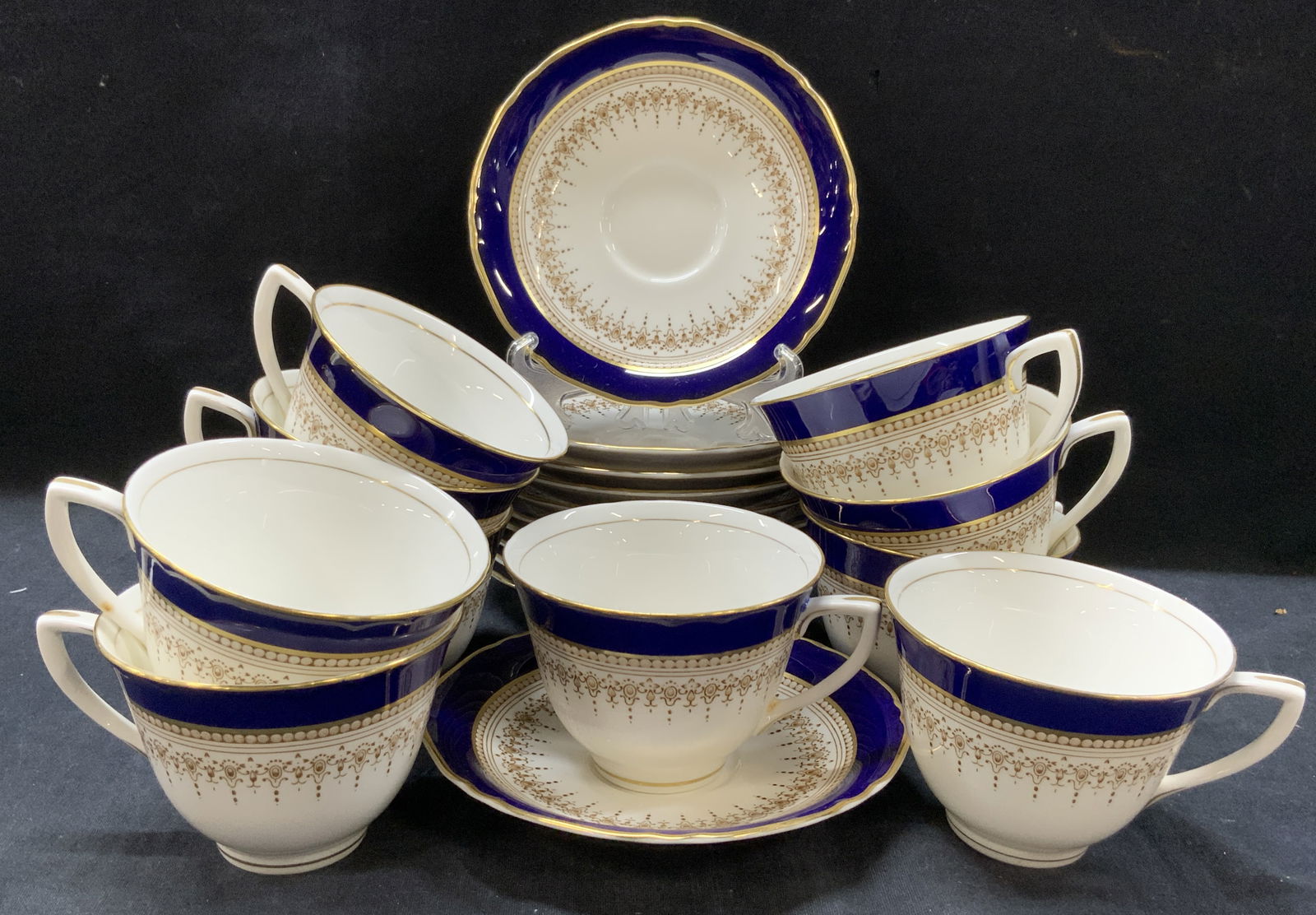 Set 21 Royal Worcester Bone China Cups & Saucers: Set of 21 total Royal Worcester fine bone China saucers and cups with cobalt blue and gilt rims on white porcelain. 10 cups and 11 saucers. Marked on underside Regency design. Made in England. Saucers