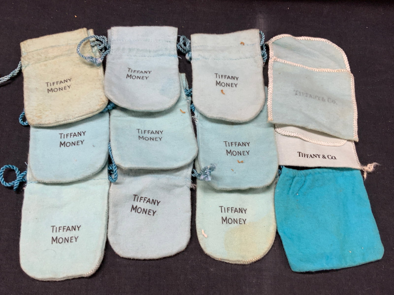Lot 12 Vntg Tiffany & Co Blue Dust Bags: Lot of 12 vintage Tiffany & Co blue bags, marked Tiffany money and Tiffany & Co all in Tiffany blue, large being 4 inches long. Evident discoloration and blemishes to blue bags. Tiffany & Co dust bags
