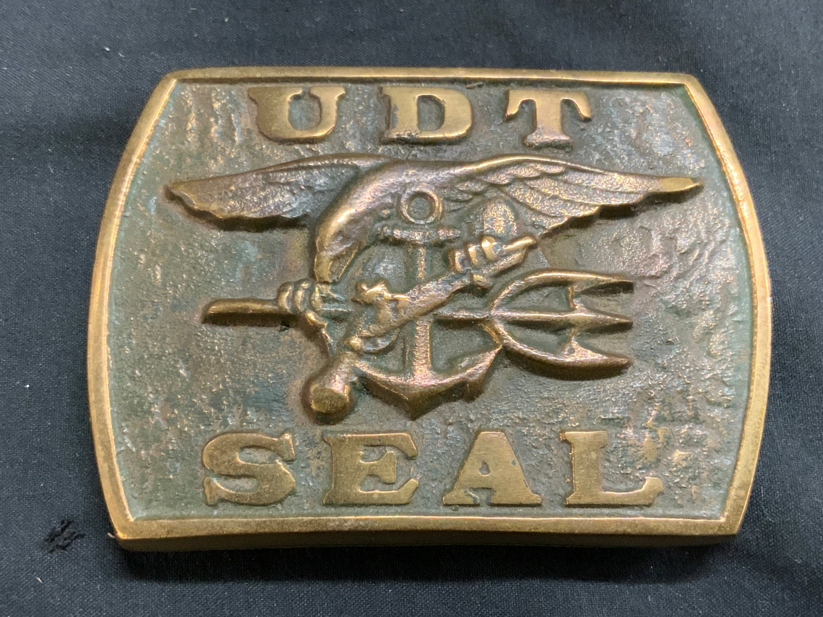 UDT SEAL Vntg Brass Military Belt Buckle: Buckle is vintage & brass. Piece reads UDT SEAL & Eagle figure with firearm, trident, & anchor. Backside has illegible inscription signature. Buckle measures approximately 3.5 inches wide 2.5 inches t