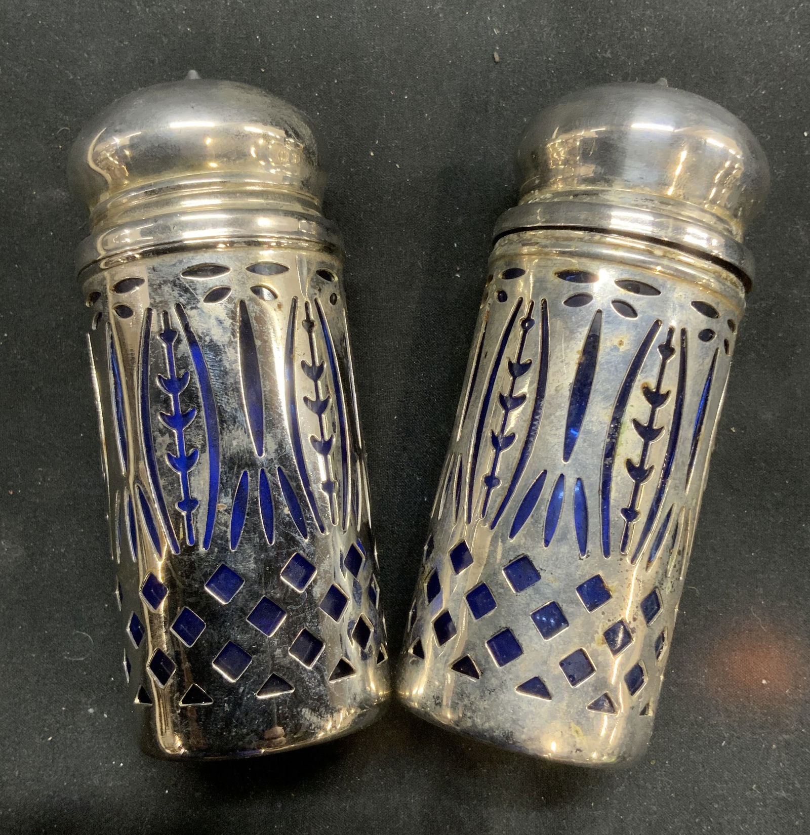 Pair Cobalt Glass Covered Salt & Pepper Shakers: Luxury table decor. Pair cobalt blue glass bottles covered in silver tone metal. Possibly a lower grade silver. Each measures approx 4 in ht. X 1.5 in. Wide. Caps screw off to fill / wash the interior