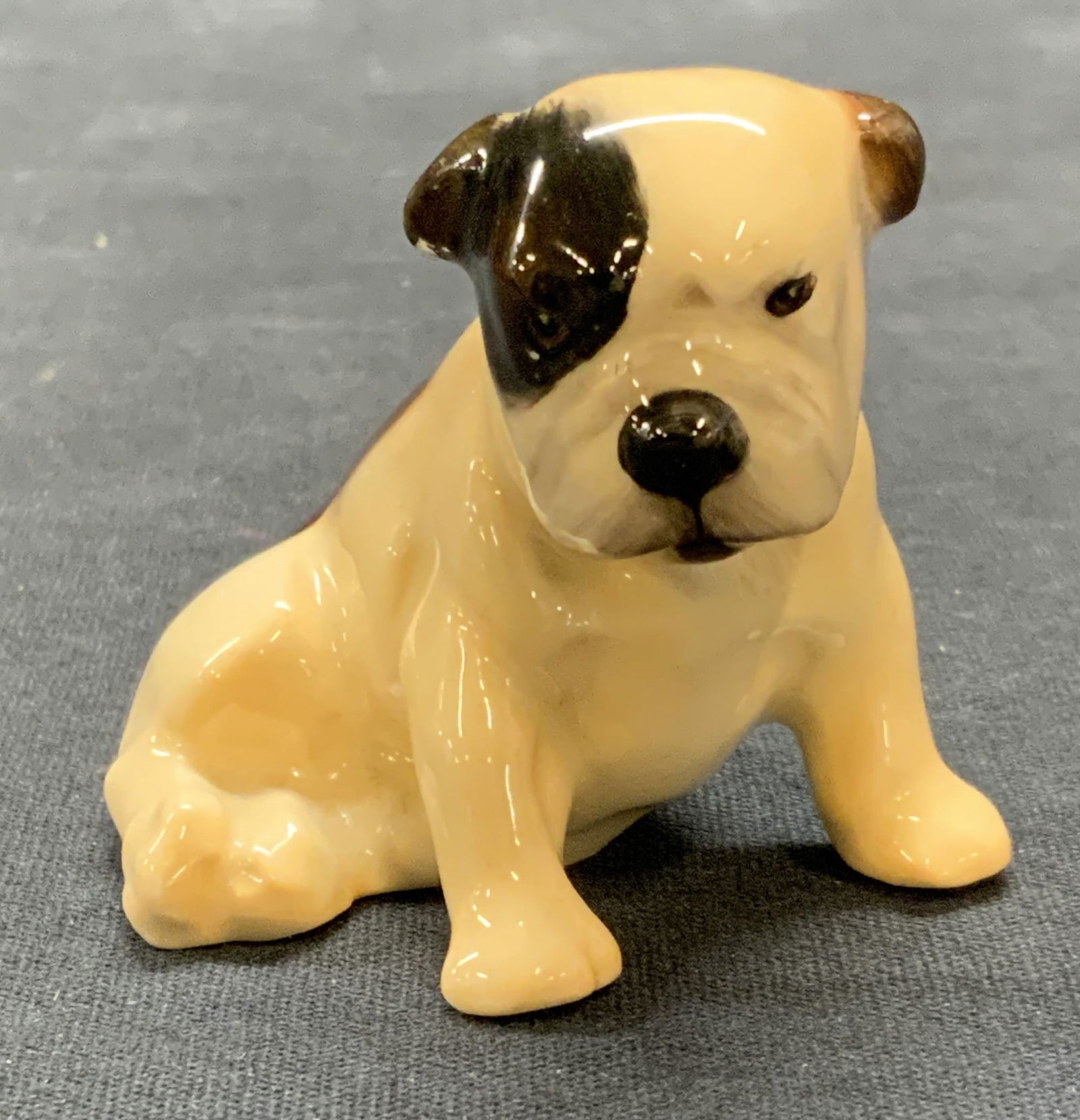 Royal DOULTON China Dog Figural, England: Royal DOULTON bone china dog figurine in tan and brown. Trademarked to underside. Made in England. Measures approx. 2.25 x 1.75 x 2 inches. Some surface wear including scratching observed. Royal DOULT