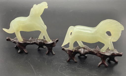 Set 2 Vintage Carved Jade Horses on Wood Pedestal: Set 2 vintage carved natural green stone horses, possibly jade, on pedestals. One horse has head down while the other has head up. Horse with its head raised measures approx. 3.5W by 3.25H