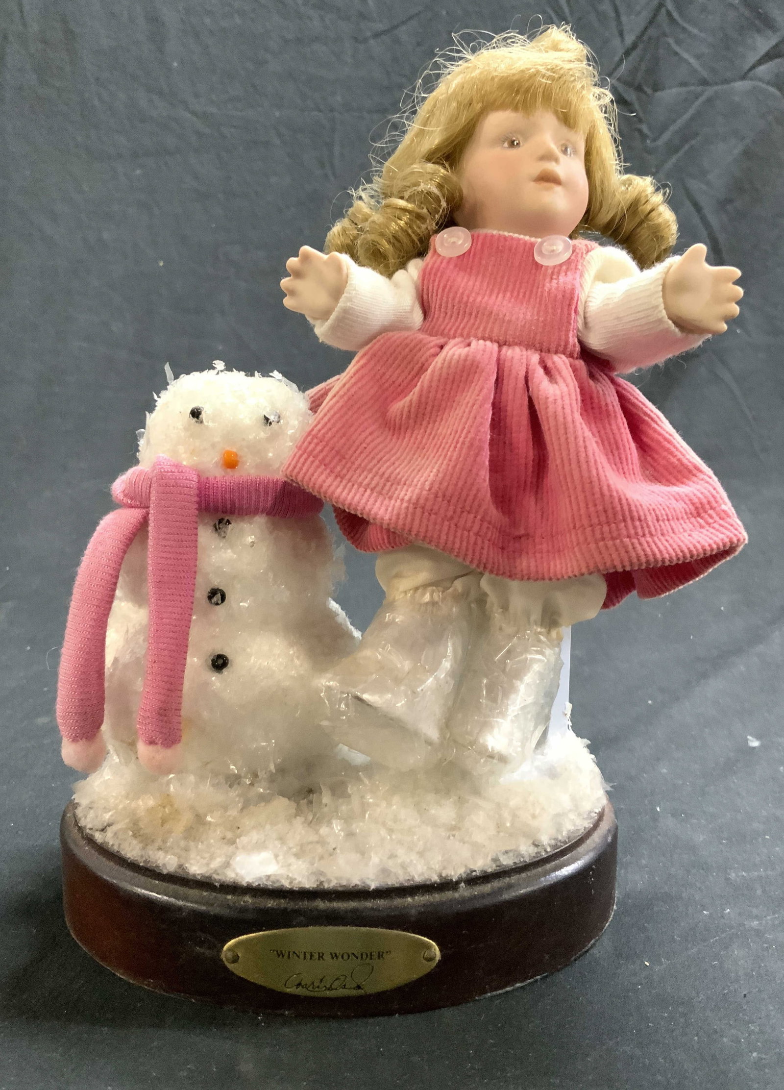 MARIE OSMOND WINTER WONDER Vntg Doll: Plaque reads MARIE OSMOND WINTER WONDER. Depicts a female child figure with snowman wearing pink scarf. Base is brown toned, possibly wooden possibly veneer. Doll with base measures approximately 8.5 