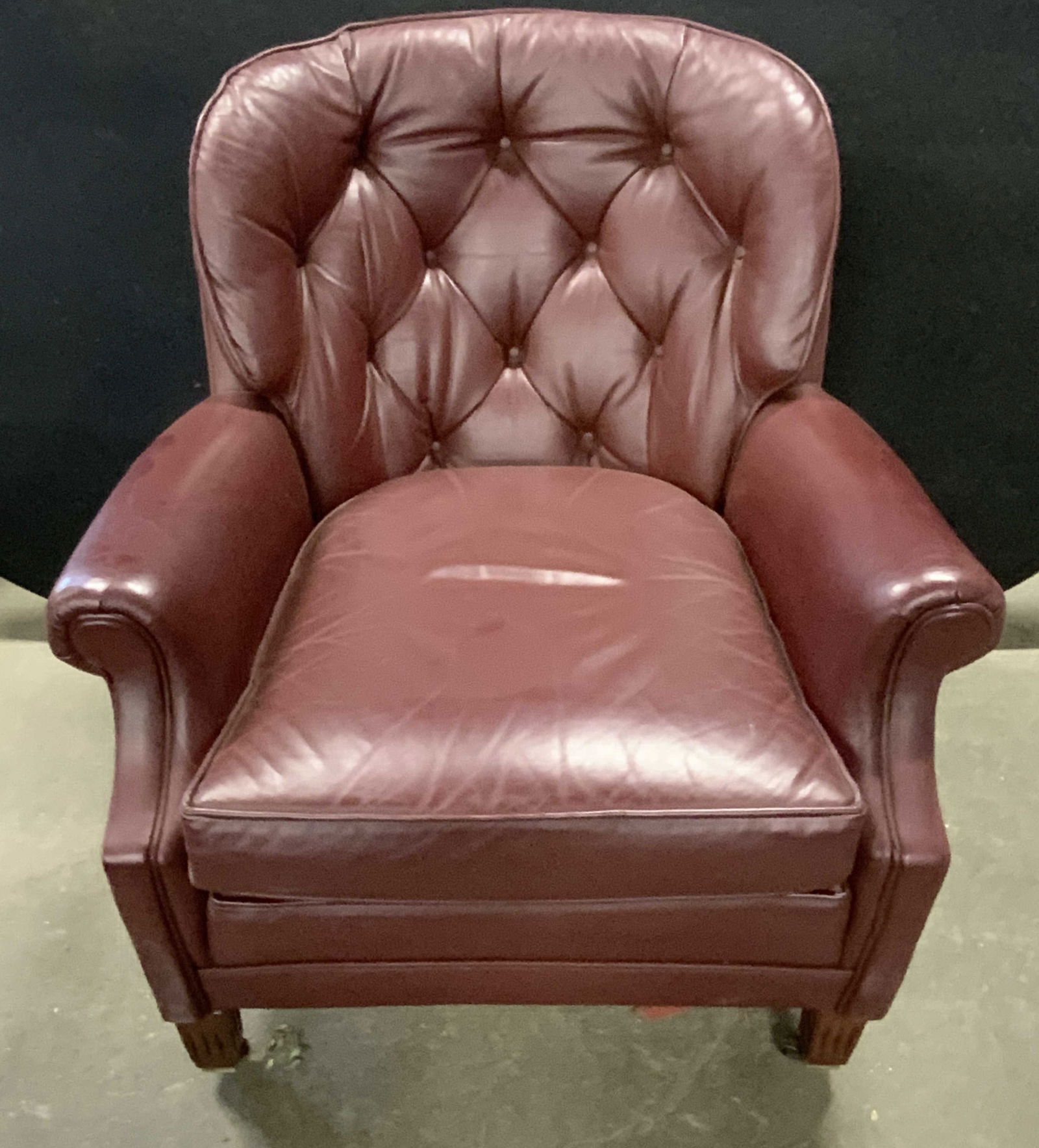 CLASSIC Tufted Burgundy Leather Armchair: A tufted burgundy hued leather armchair. Casters to the two front feet. Tag to underside reads BY CLASSIC, GENUINE TOP GRAIN LEATHER. Other tag reads MAHOGANY, FABRIC AND COLOR, ADELAIDE AND VINEYARD.
