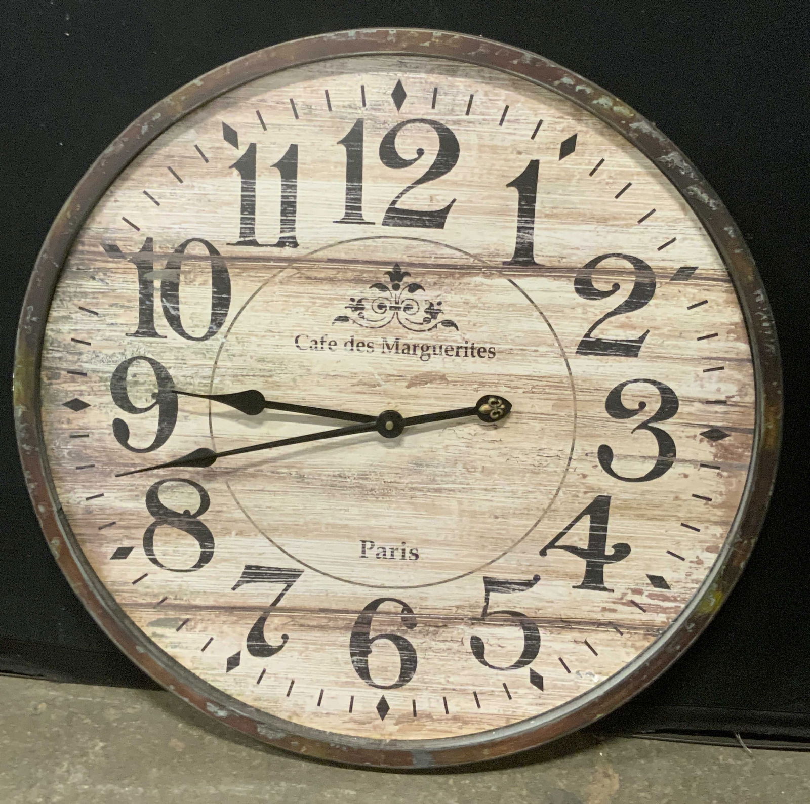 WORLD MARKET Circular Wooden Wall Clock: A circular wooden wall clock. Distressed finish. Obverse reads CAFE DES MARGUERITES PARIS. Sticker to reverse reads WORLD MARKET, $49.99. Measures approx. 24.5L x 24.5W in. Not tested for function. Su