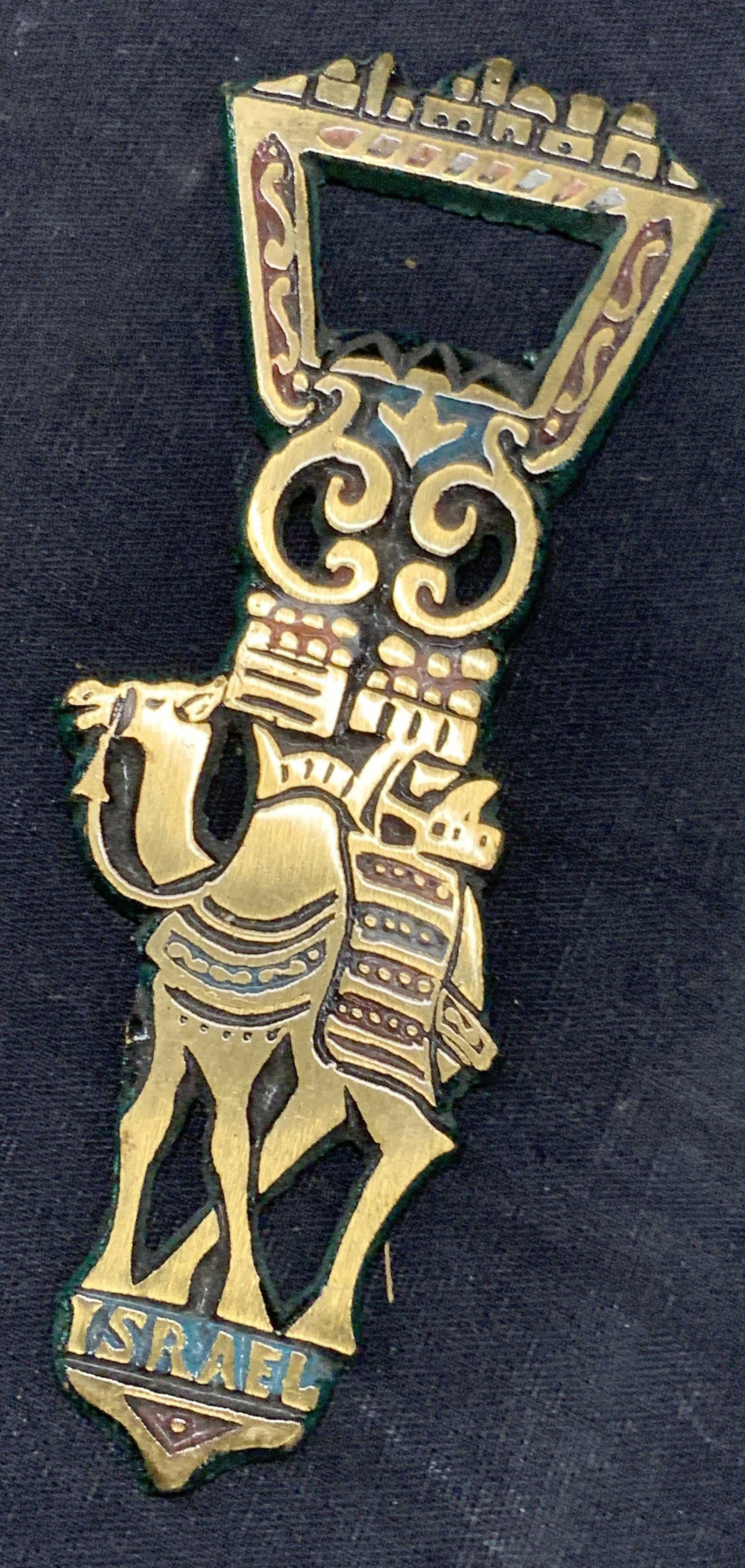 Vntg Brass & Enamel Camel Bottle Opener, Israel: Vintage brass and enamel bottle opener with the image of a camel on the handle, marked Israel. Approx 5 inches long and 2 inches wide. Moderate discoloration and wearing to enamel on metal. Brass ware