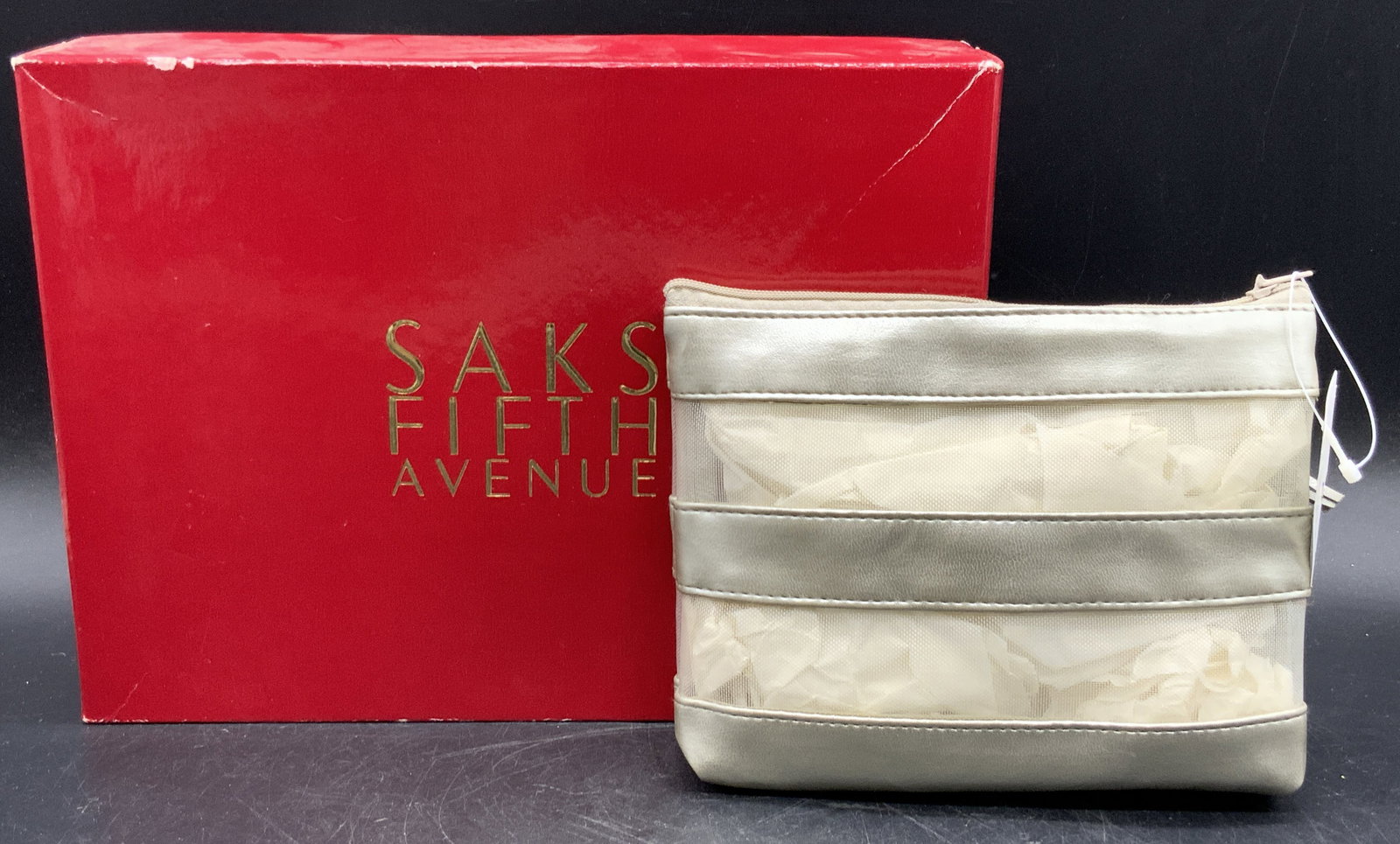 SAKS FIFTH AVE Cosmetic Bag W/ Saks Fifth Gift Box: A pewter tone metallic leather and mesh cosmetic bag. Zipper closure. Original tag attached. Comes in red SAKS FIFTH AVE gift box. The box measures approx. 2H x 10.25W in. Some wear consistent with ag