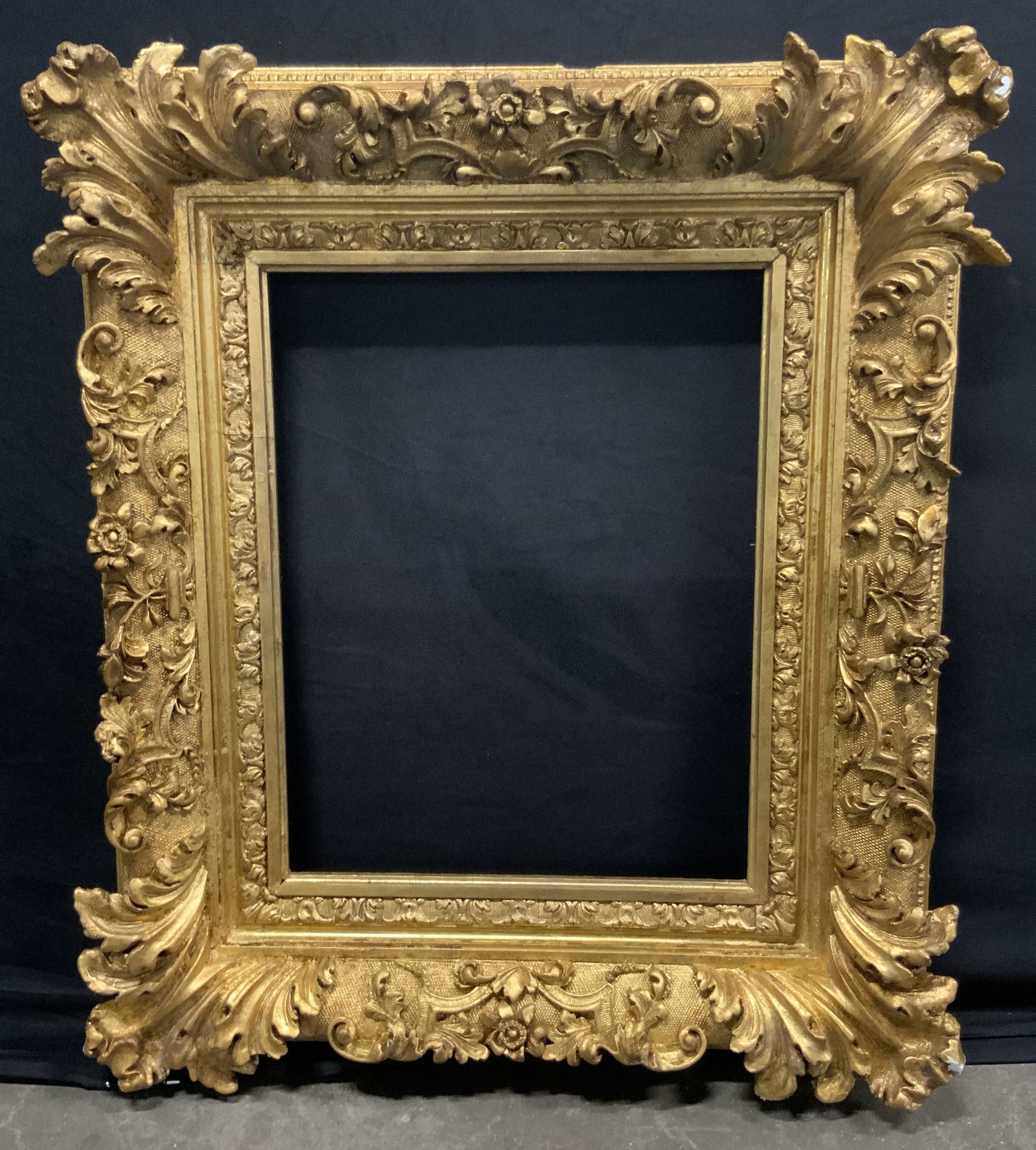 Vintage Ornate Gold Leaf Wood Frame: A vintage ornate frame crafted from wood & plaster and finished with gold leaf. Scrollwork designs in relief alongside floral & foliage motifs. Metal hardware to reverse for display. Frame Measures ap