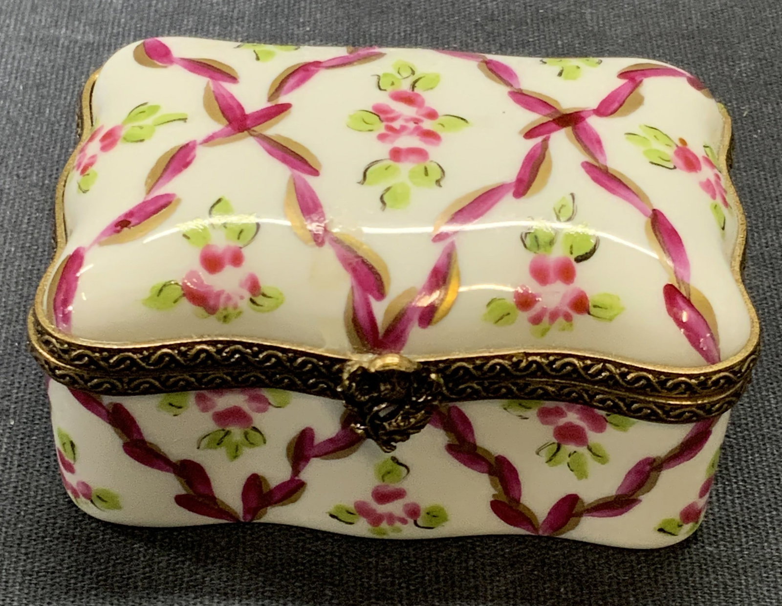 LIMOGES FRANCE Hand Painted Porcelain Pill Box: A vintage hand painted French porcelain pill box. Florals throughout the piece. Piece opens with metal hinge hardware which features a floral motif to the obverse. The underside is signed, PEINT MAIN,