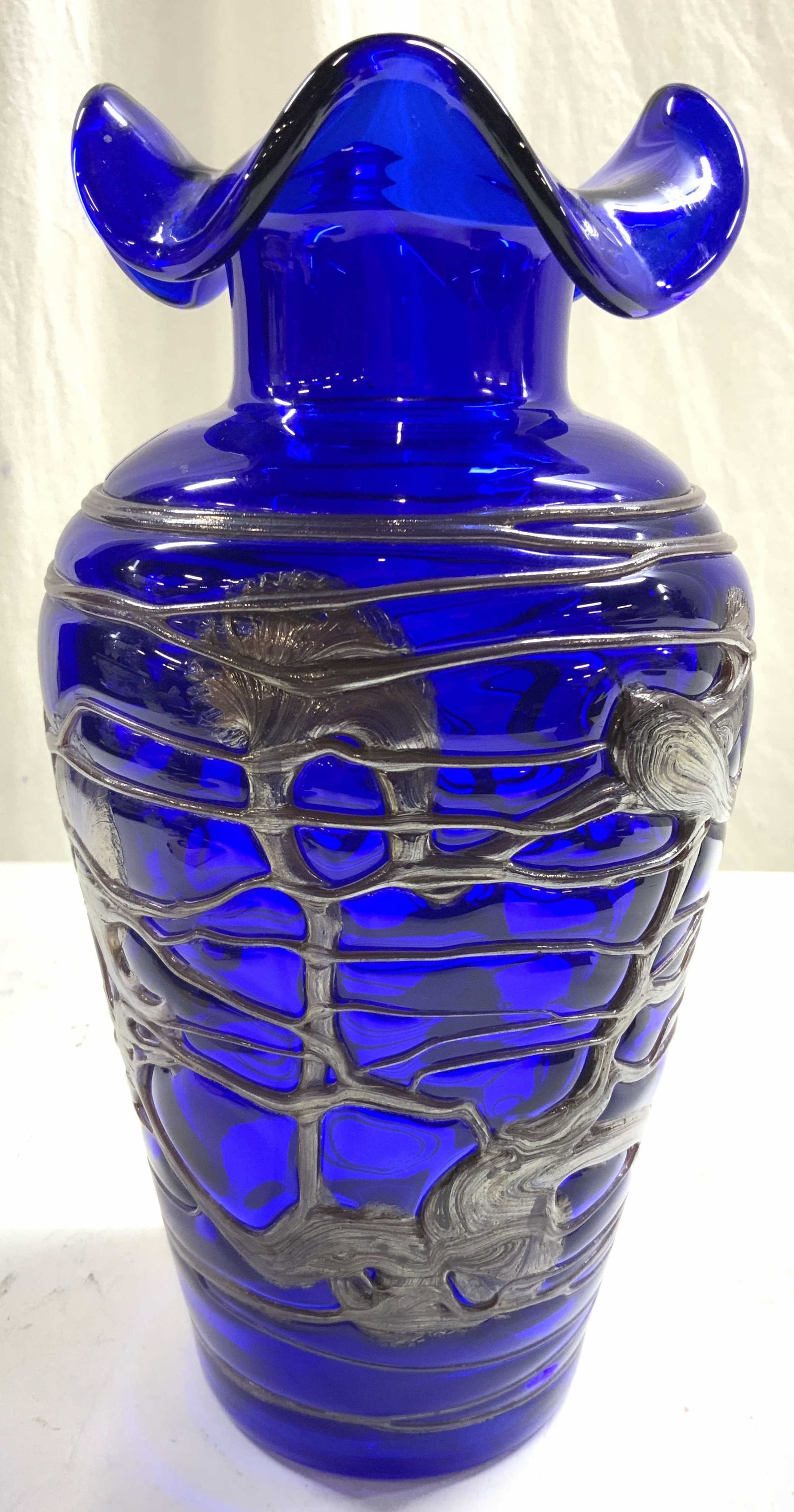 Cobalt & Mettalic Art Glass Vase 11.5in: Vase is cobalt blue toned with silver toned metallic glass detail around exterior. Vase has handkerchief style rim. General surface wear including scratches. Vase measures approximately 11.5 inches ta