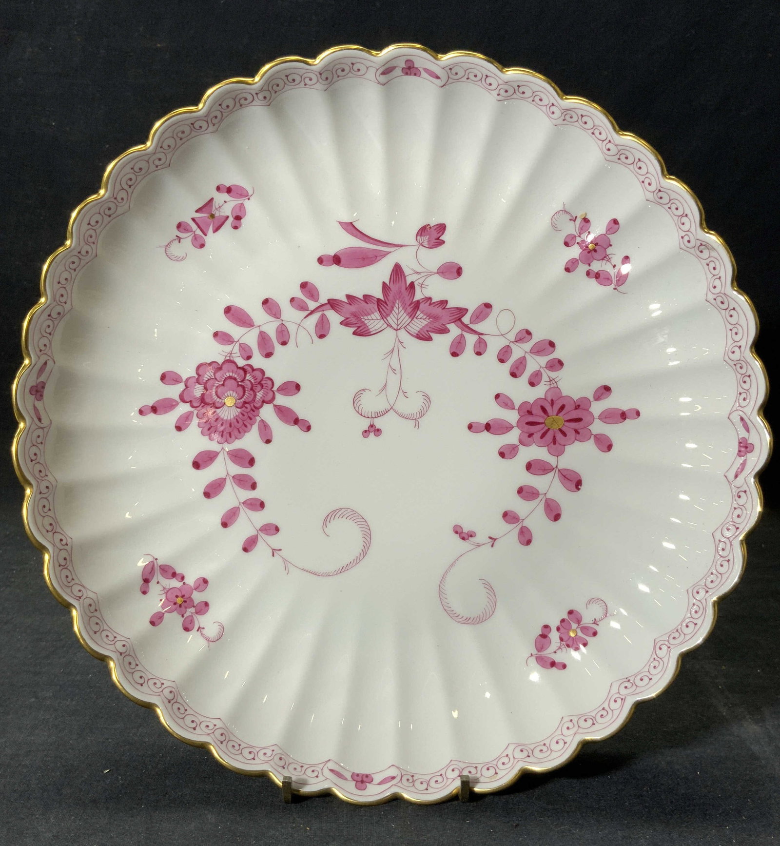 MEISSEN Vntg Scalloped Porcelain Plate: Underside has MEISSEN crossed sword trademark and reads 340470/77. Plate has scalloped sides. Piece has gilt rim. Plate has magenta toned floral, vine and leaf detail. Piece measures approximately 11 