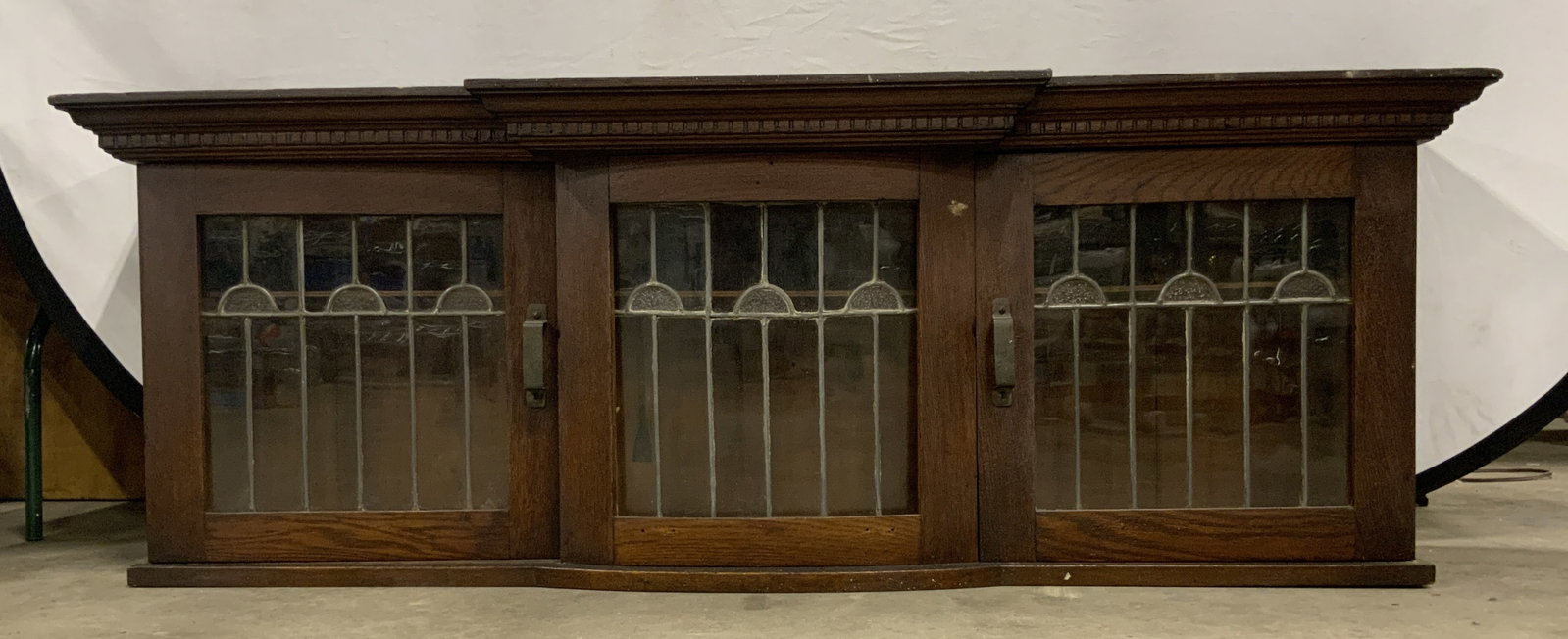 Vintage Wooden Wall Shelf W/ Soldered Glass Panels: A vintage wooden wall shelf featuring soldered glass panels. Two doors open to reveal storage to interior. Measures approx. 19.5H x 13D x 55W in. Some losses, chipping, discoloration, and surface wear