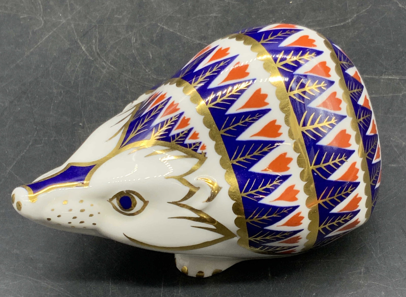 Royal Crown Derby English Porc Hedgehog Figural: A vintage Royal Crown Derby English porcelain hedgehog figural in traditional Imari colors with gilt line work. Gold tone button to the underside. Measures approx. 2.25H x 4.25W in. Underside signed R