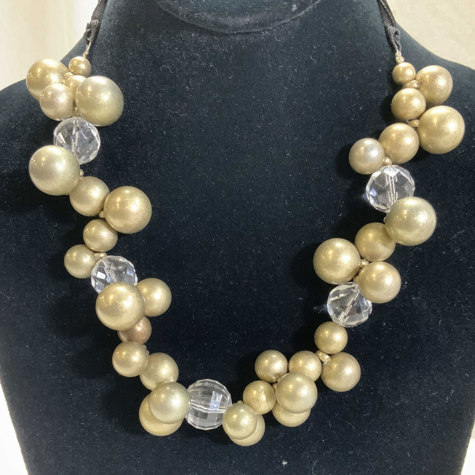 Chunky Orb Bunch Beaded Necklace w Tie Ribbon: Gold tone metal orb-bunch beads accented with clear faceted beads. Long black tie ribbon for desired length. 1.25 in. W design, 39 in. total length . Necklace, beaded gold tone metal and clear faceted