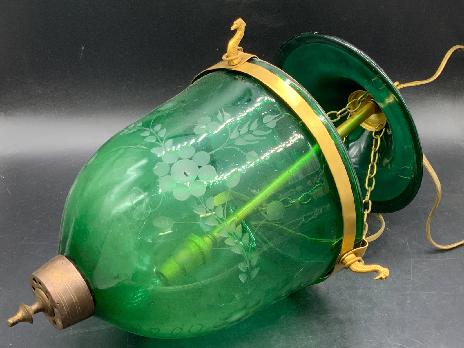 Vintage Green Glass Pendant Light: A vintage green glass pendant light with a frosted floral and foliage motif to the sides. Brass hardware. Brass bird motifs to the sides. Measures approx. 17.5L x 8.5W in. Some holes to the glass. Som