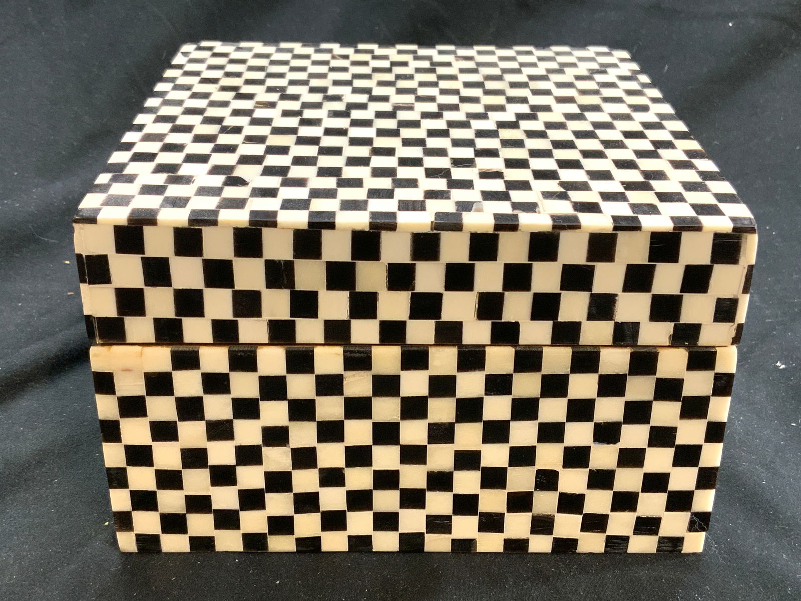 Checkered Bone Mosaic Wood Keepsake Box: Keepsake box has checkered black and white toned exterior, appears to be bone. Interior of piece is tan toned and wooden. Box has square prism form. Piece measures approximately 6 inches square 3.75 i
