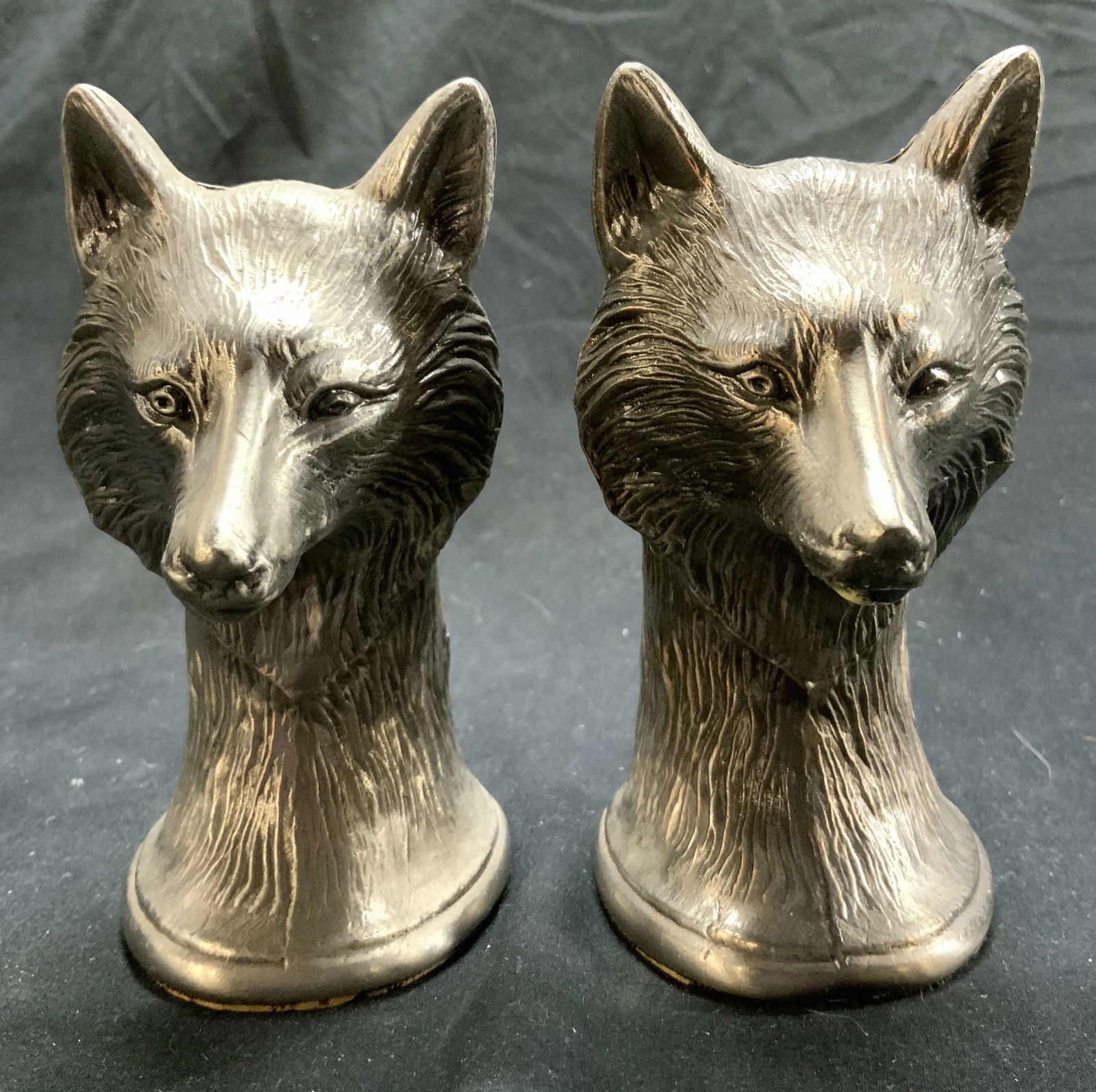 Pair Pewter Wolf Paperweight: Lot includes 2 paperweights. Each have wolf head form. Paperweights each have intricate relief detail to show fur texture and facial detail. Undersides have cork. Each piece measures approx 4.75 inche