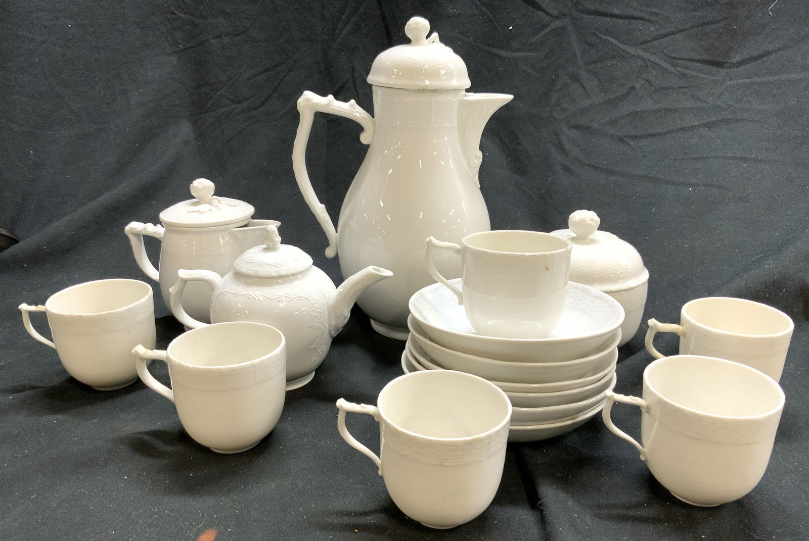 KPM Set 16 Vntg Porc Tea/Coffee Service White: Undersides have KPM trademark. Each piece is white with woven style relief detail at edges. Lot includes 1 teapot with lid, 1 creamer dish with lid, 1 sugar dish with lid, 1 small teapot with lid appe