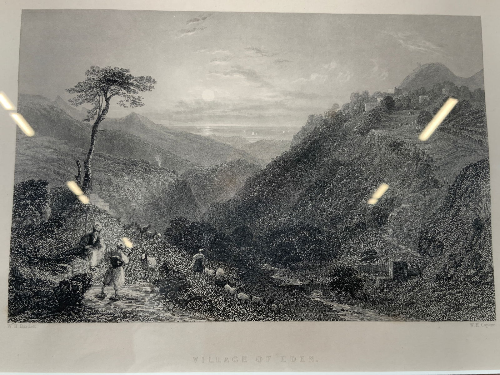 1841 Antique W.H. Capone Engraving Village of Eden: Engraving Lithograph on paper. Artist name in lower right corner. W.H. Capone. Caption reads Village of Eden. Subject depicts men walking sheep into a valley with buildings and lush shrubbery. Framed