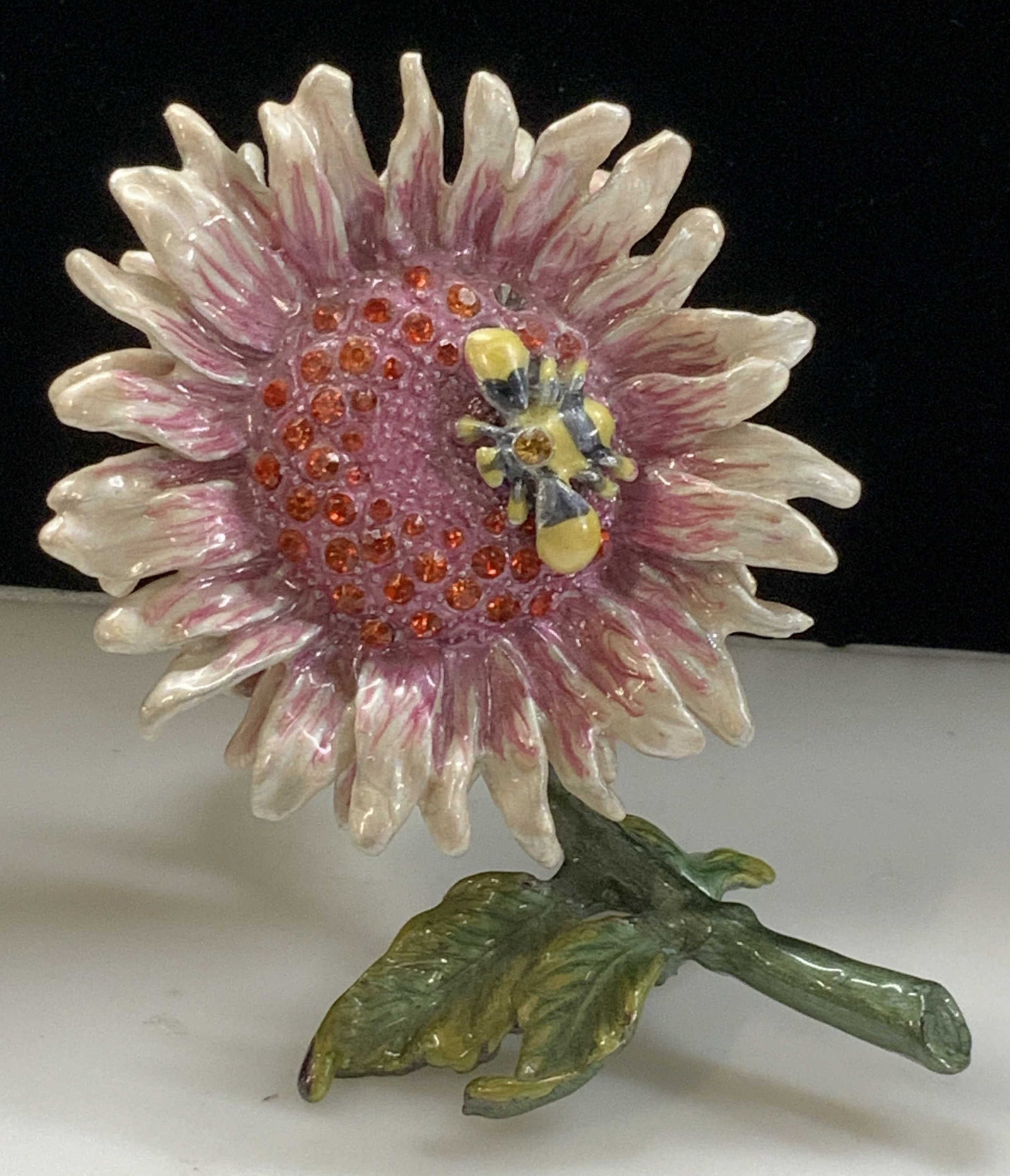 Enamel Sunflower Magnetic Pill Box: Sculptural magnetic pill box. Enamel sunflower with green stem. Bee on the flower. Pill box is in an upright position. Front of flower is magnetic and reveals a small depression for pills, jewelry or 