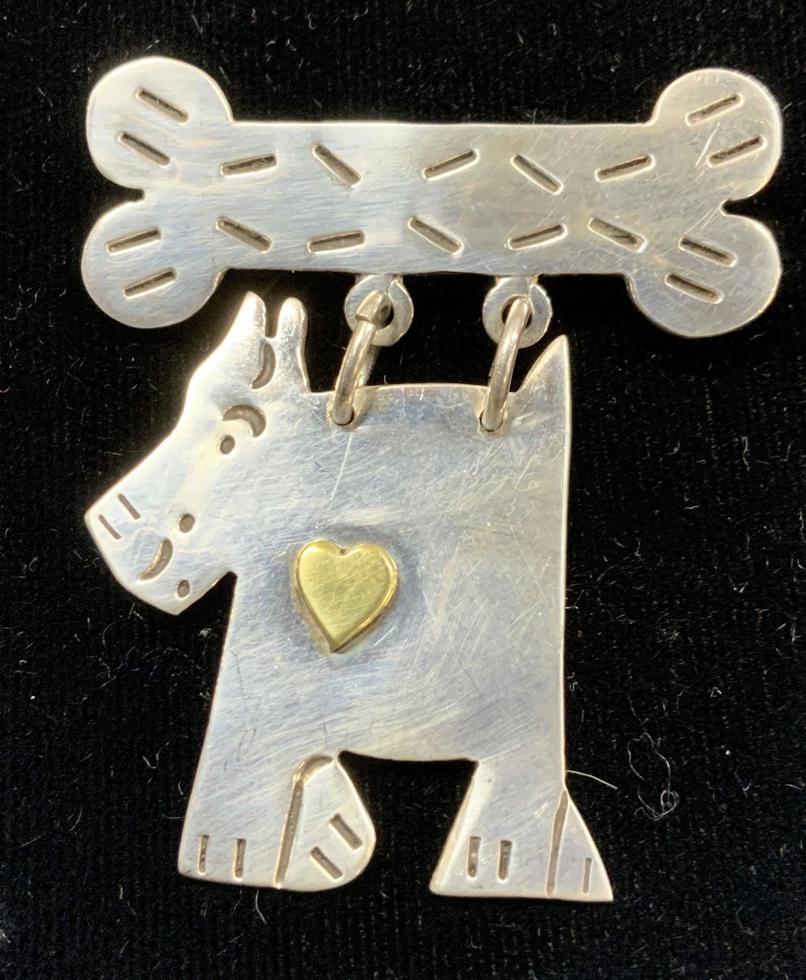 MWS Mexican Sterling Silver Dog & Bone Brooch: Arts and crafts hand made sterling silver brooch. .42 ozt . Dangling dog from a dog bone. Marked .925, Mexico, and MWS. Measures approx 2 in. Long x 1.5 in. Wide. Folk art sterling silver dog brooch,