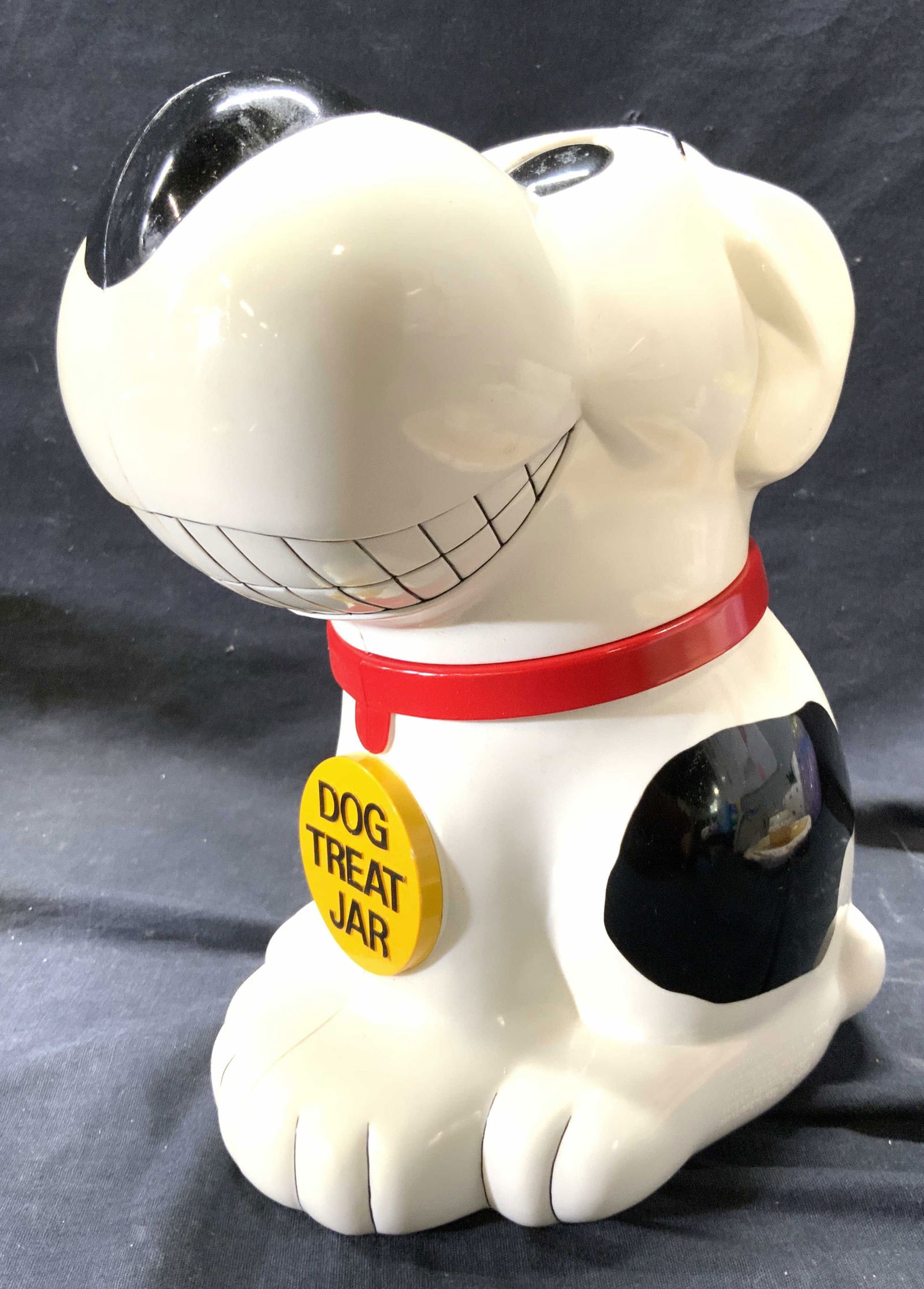 FUNDAMENTAL TOO LTD Dog Treat Jar: Piece reads FUNDAMENTAL TOO LIMITED. Jar is plastic. Piece has seated dog form, depicting a black & white toned smiling dog with red collar which reads DOG TREAT JAR. Head acts as lid, opens to vessel