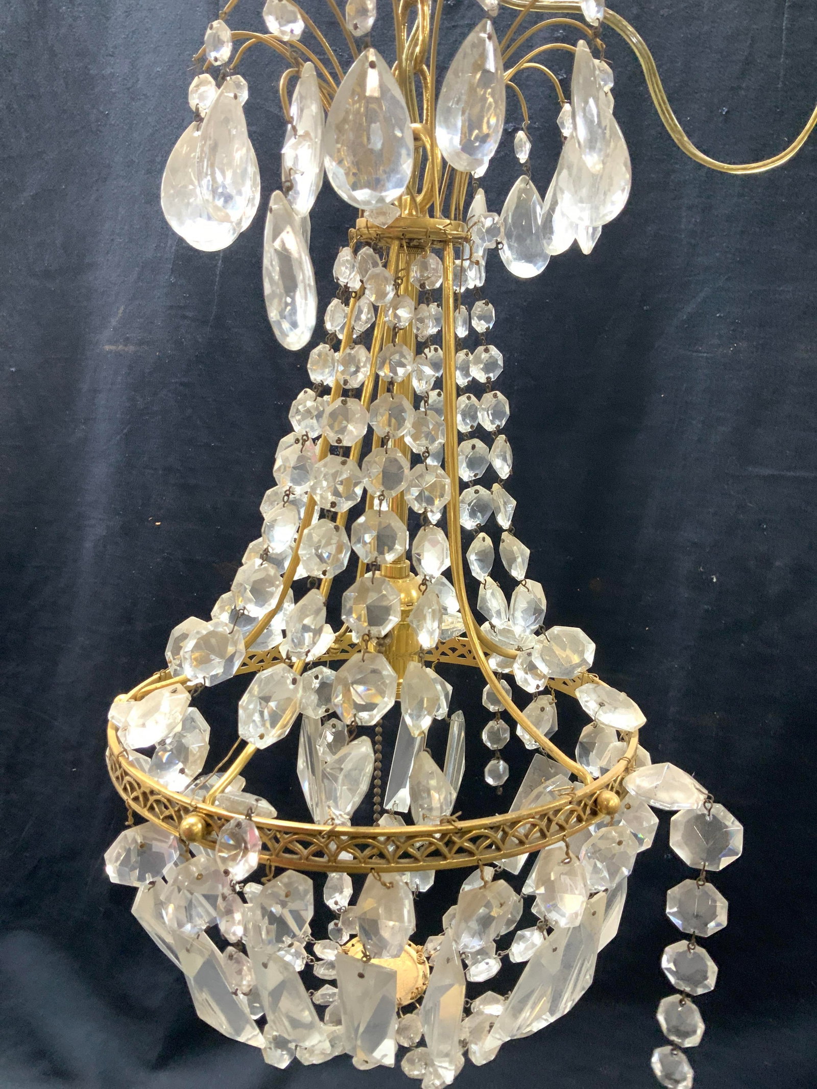 Gold tone Prism Pendant Chandelier.: pull chain singular light bulb gold tone chandelier with strings of faceted prisms along the body and dangling from the lower rim into a demilune shape. Prisms will need to be re- attached , some repl