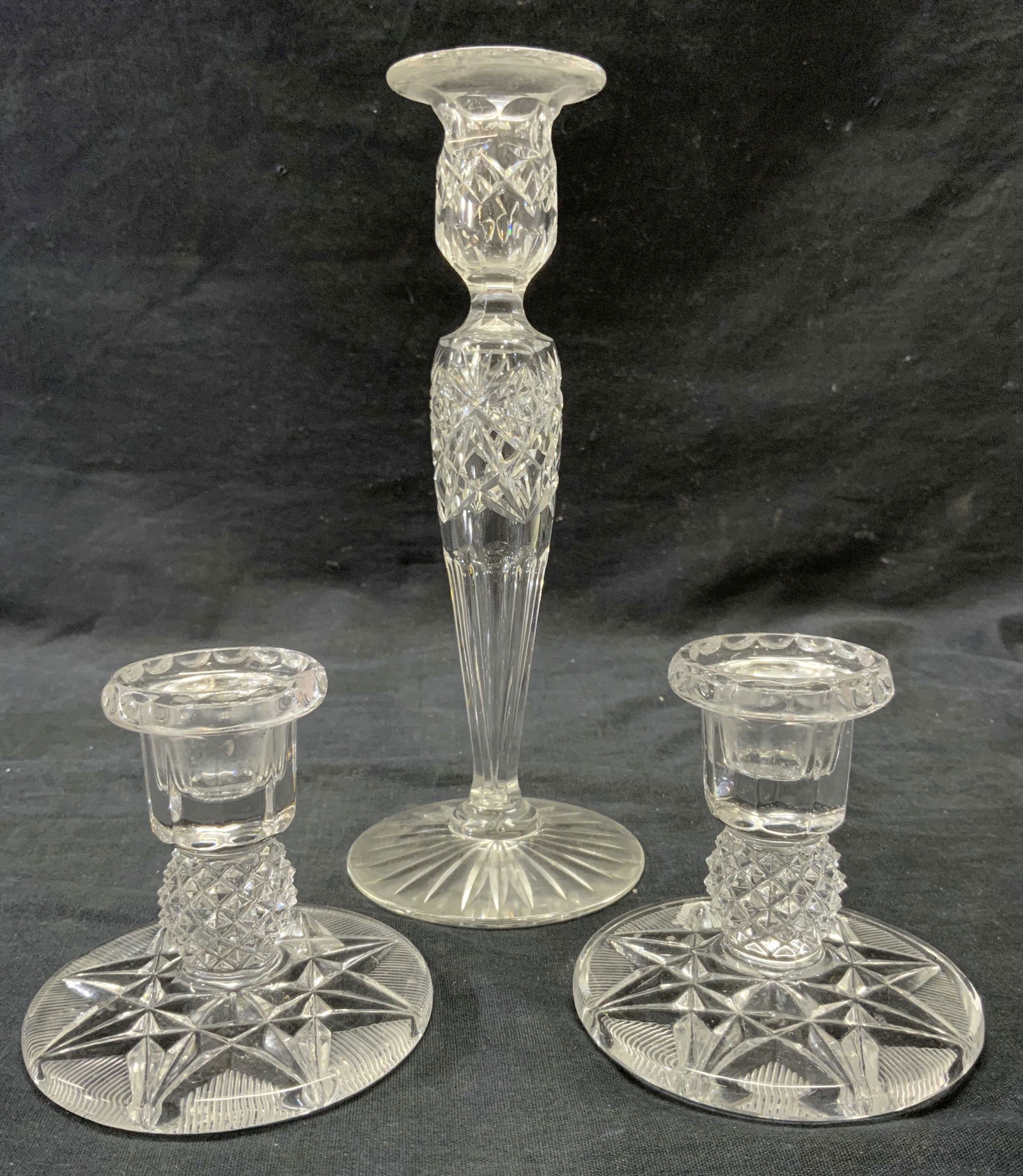 Lot 3 Cut Crystal Candlesticks: Lot includes a pair of candlesticks & 1 additional candlestick. Each piece appears to be cut crystal. Candlesticks each have intricate geometric relief detail. Largest piece measures approximately 9 i