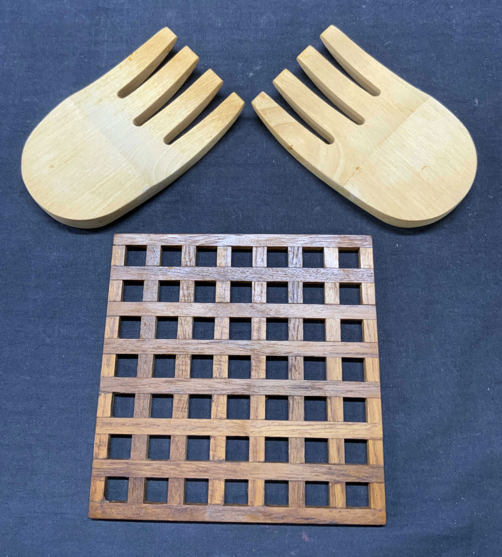 Lot 3 Wooden Trivet & Salad Serving Fork Heads: Lot includes 1 wooden gridded trivet, and a pair of salad serving fork heads. Each piece is wooden. Trivet is light brown toned, fork heads are tan toned. Trivet measures approximately 7 inches square