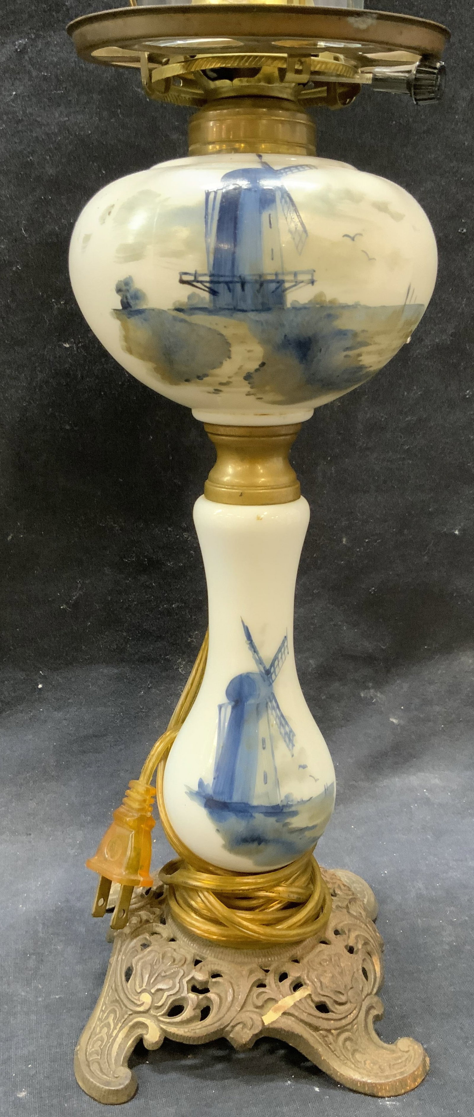 Hand Painted Windmill Hurricane Glass Lamp: Lamp is glass and gilt metal. Piece appears to be vintage. Lamp is hand painted with windmill detail. Top of lamp has hurricane glass structure. Piece has ornate gilt metal base with scrolled feet. La