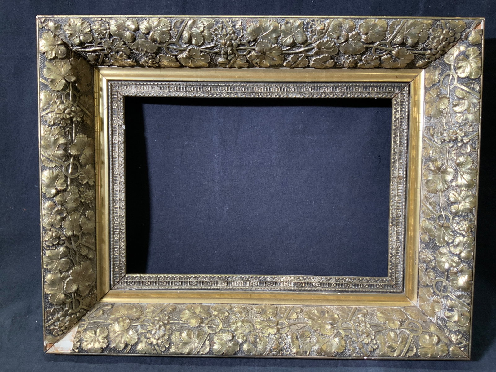 Gilt Wooden Frame Raised Foliage Motif: Gilt wooden frame with raised foliage motif. Inner frame has raised patterned motif. Verso has vertical rabbet and hanging wire. Frame measures approx. 19.5 W x 15.5 H in. Window measures approx. 13 W