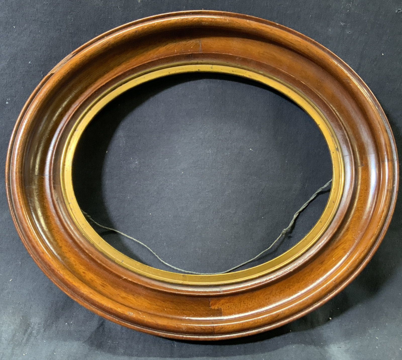 Wooden Oval Gilt Accented Picture Frame: Wooden frame with gilt accent on inner window. Frame measures approx. 13.5 W x 11.5 H in. Window measures approx. 9 W x 7 H in. Minor wear and chipping to frame. No framing teeth on verso. Picture fra