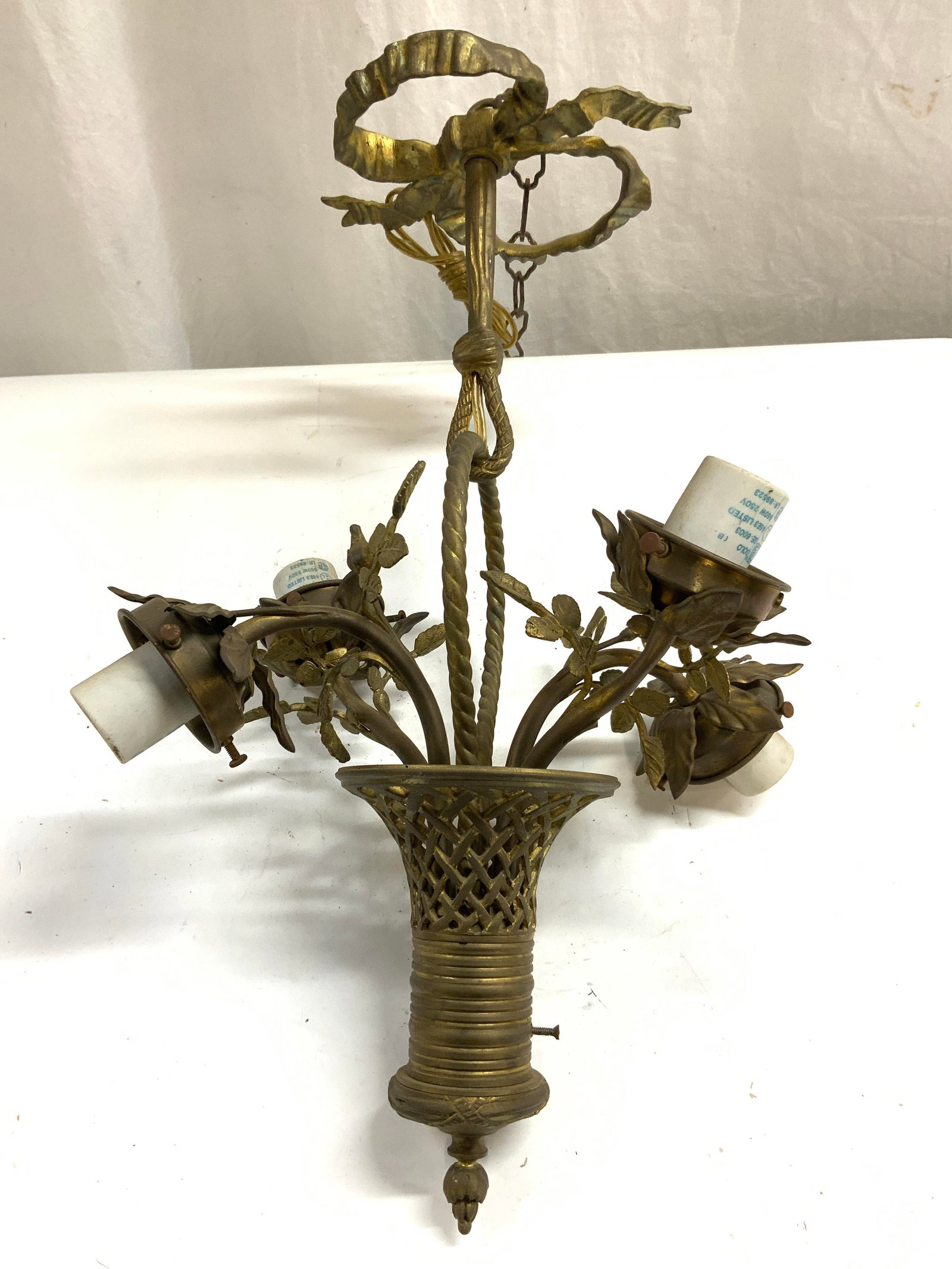 Vintage Gilt Metal 4 Arm Chandelier: Chandelier is gilt metal. Piece is vintage. Chandelier has 4 arms each with vine & leaf detail. Top of chandelier has ribbon structure & chain link . Chandelier without chain link measures approximate