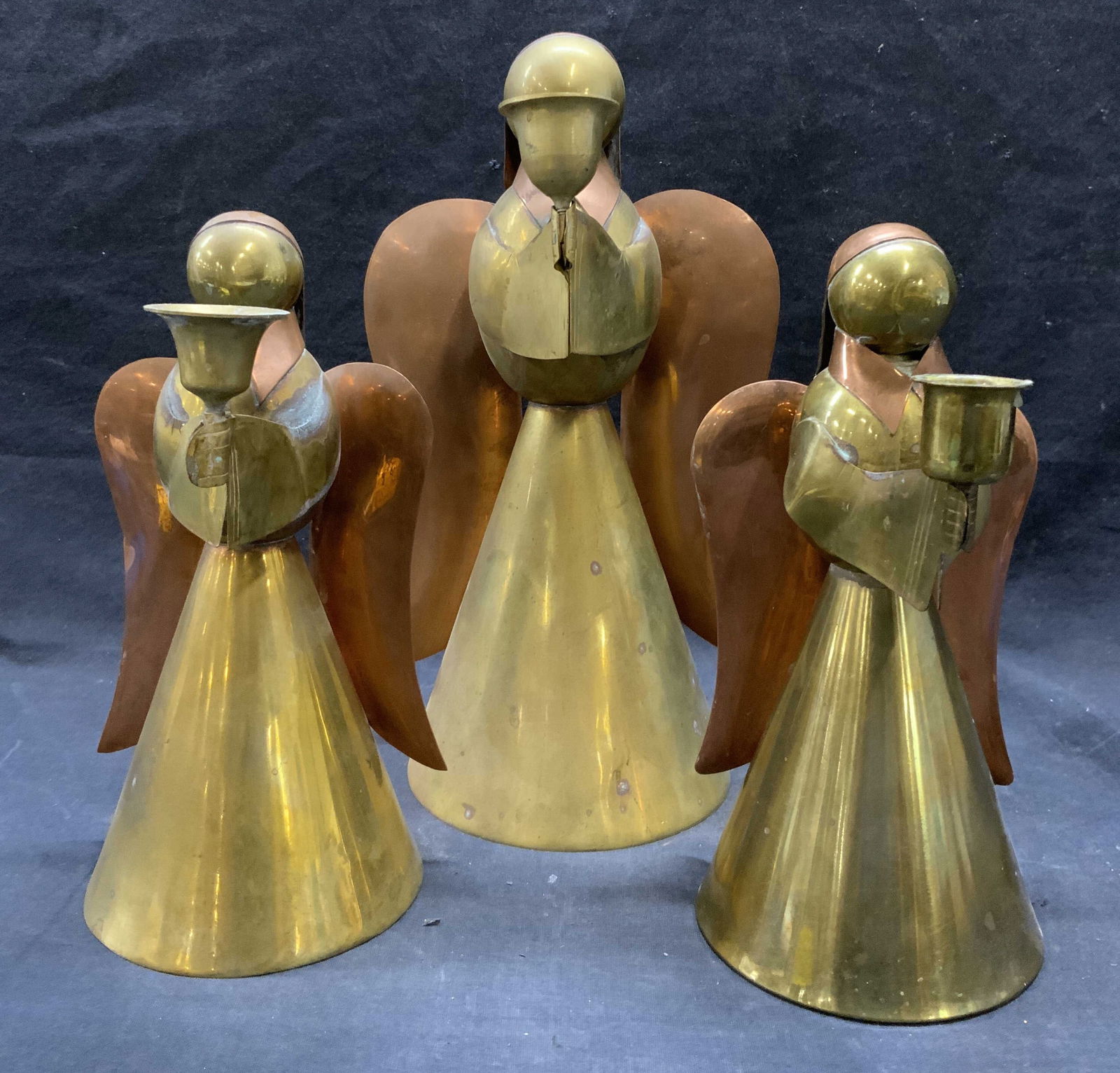 3 Vntg Brass & Copper Angel Figure Candlesticks: Lot includes 3 angel figures. Each are brass and copper. Each angel figure appears to be vintage. Angel figures each holding vessel in front to place candle. Largest candlestick measures approximately