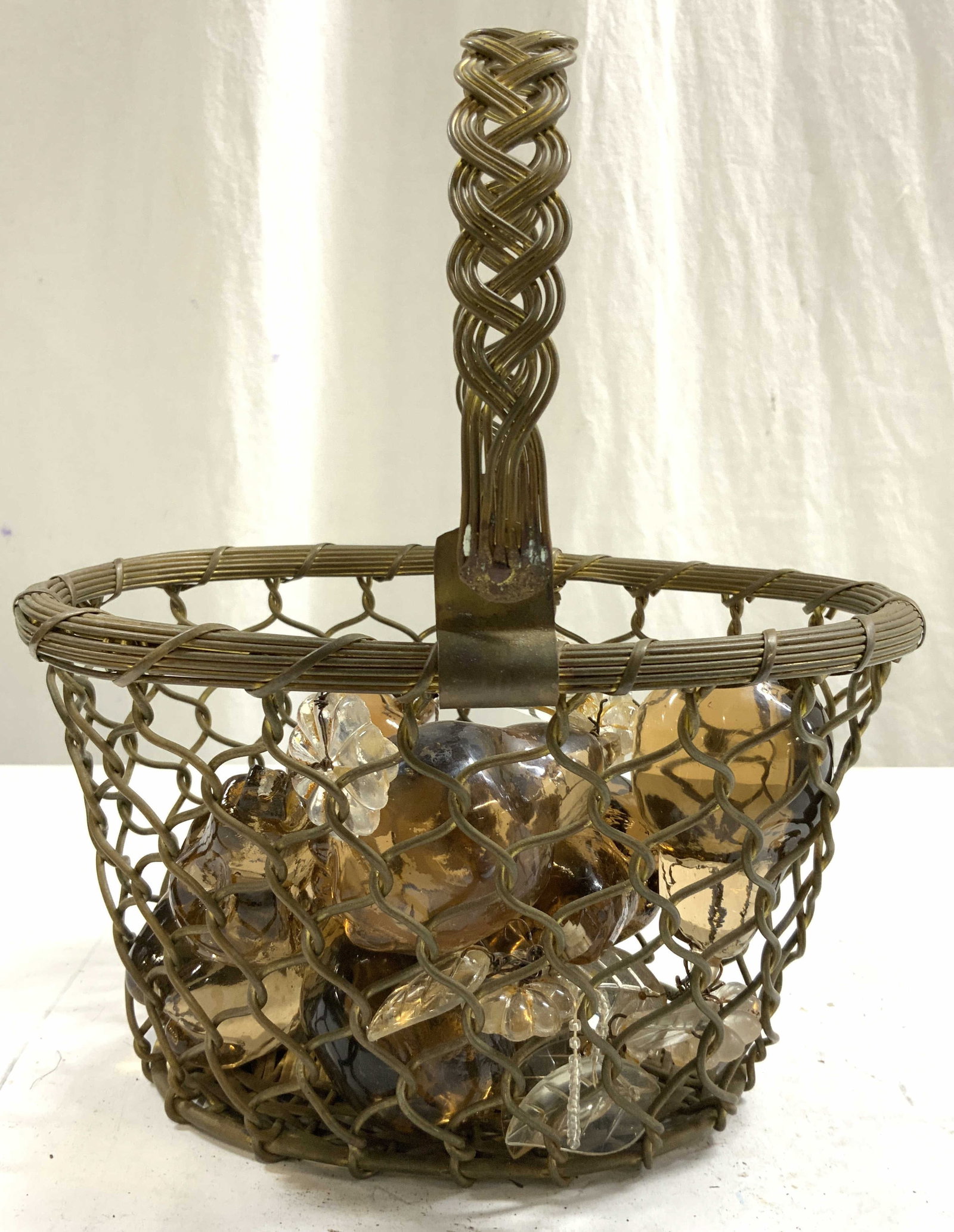 Lot 10 Brass Basket & Art Glass Fruit Ornaments: Lot includes 9 Art glass fruit chandelier ornaments & 1 brass basket. Basket has woven structure. Piece has arched handle. Each ornament is glass and has tan amber tones. Basket measures approximately