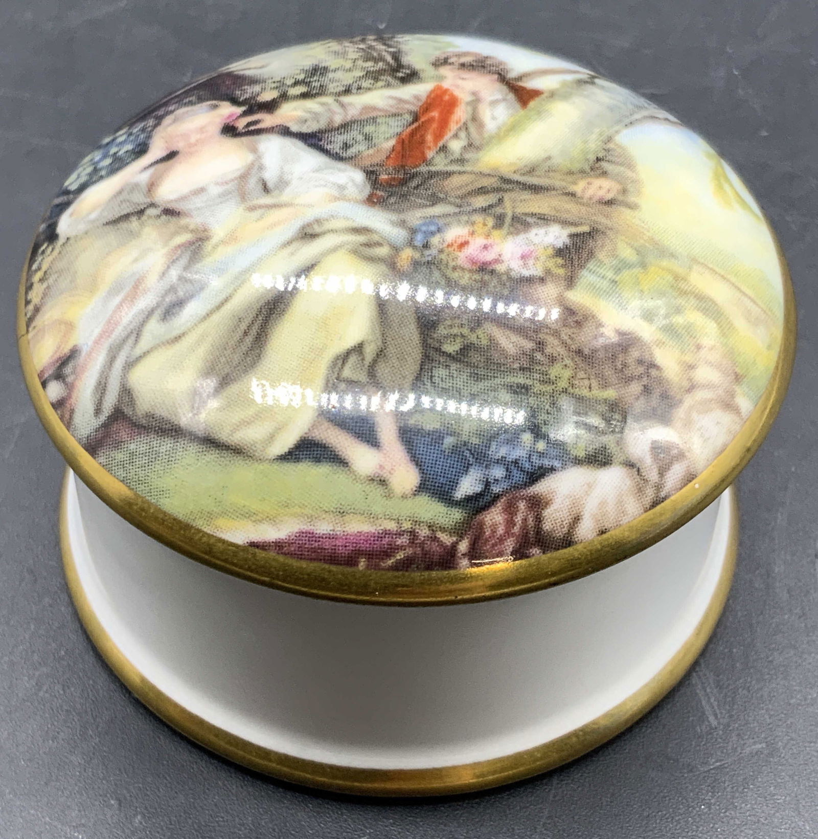 CROWN STAFFORDSHIRE English Trinket Box, Lidded: An English fine bone china Crown Staffordshire trinket box. Lidded. The lid features two people in a nature scene. Measures approx. 1H x 2W in. Underside signed CROWN STAFFORDSHIRE. Crazing and surfac