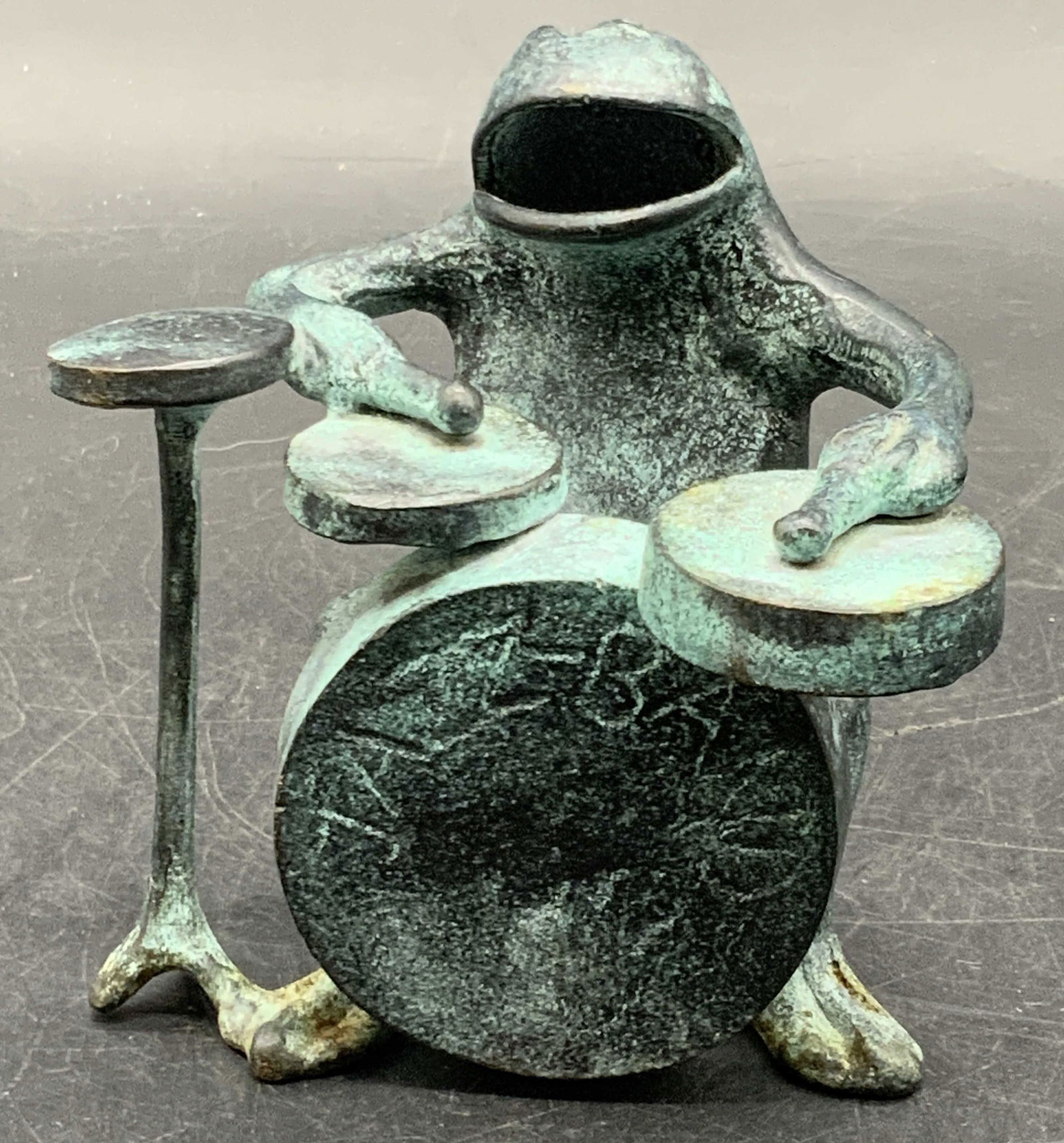 Vintage Metal Jazz Band Frog Figural: A vintage metal, possibly brass, jazz band frog figural. The frog is depicted playing the drums. The obverse reads JAZZ BAND. Measures approx. 3.75H x 3.75W in. Patina present. Some surface wear and d