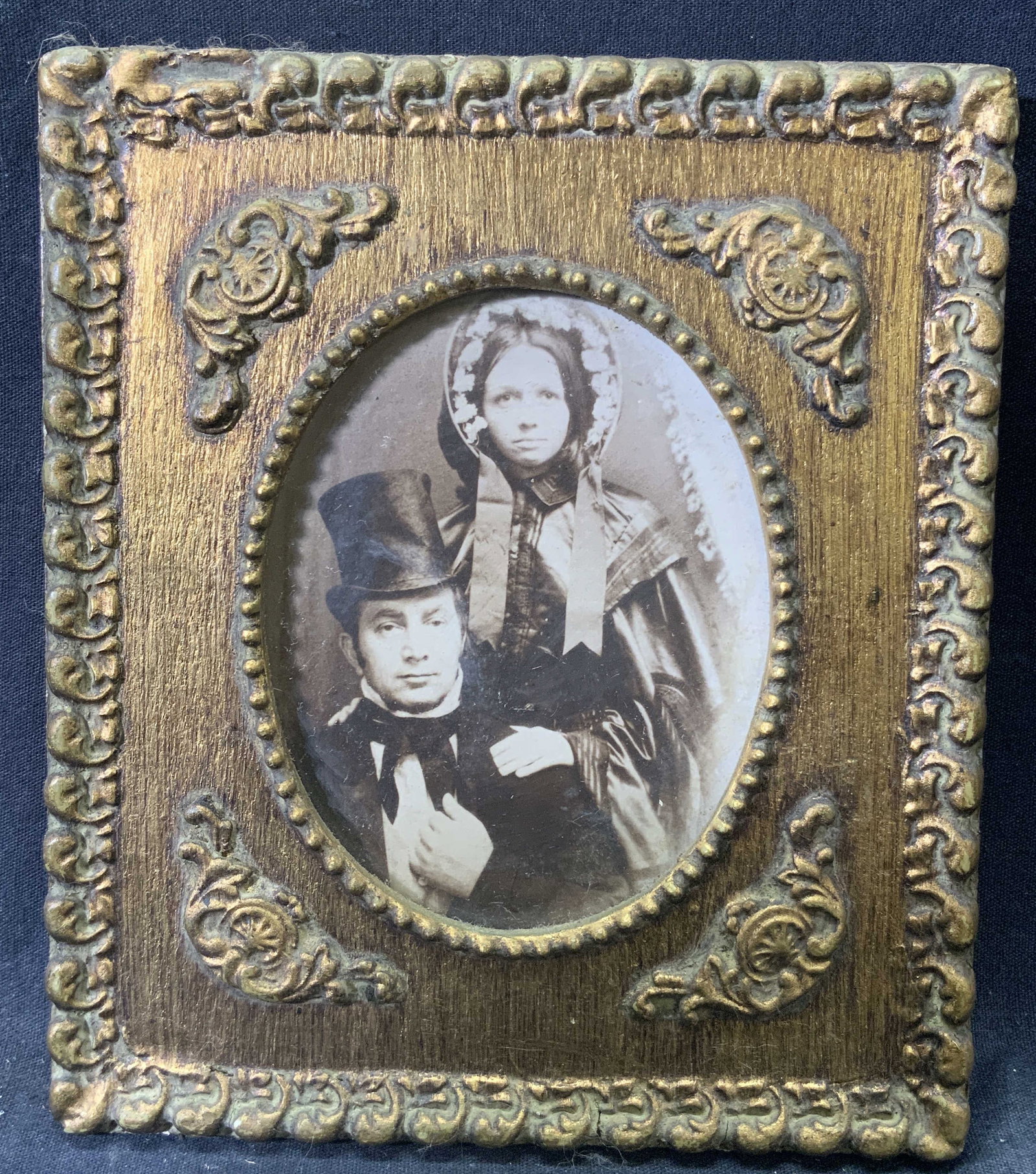 Antique Photograph in Gilt Wooden Frame: Antique photograph. Subject depicts a man and a young woman posing for their photo. Framed in gilt wooden frame with raised scrolling motifs. Frame measures approx. 6.5 W x 7.5 H in. Window measures a