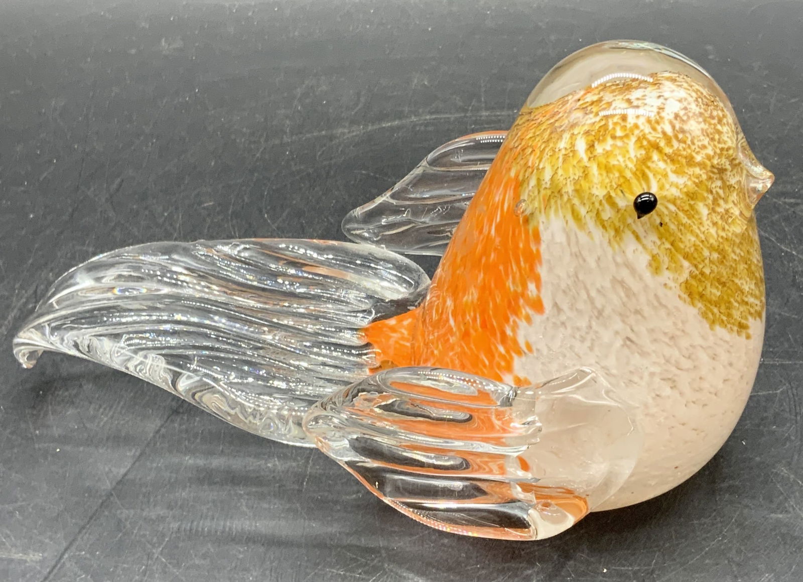 Art Glass Bird Figural Paperweight: A clear, orange, white, and gold toned art glass bird figural / paperweight. Thick walled and weighty. Measures approx. 4H x 6W in. Some bubbles to the glass. Some imperfections to the glass. Chipping