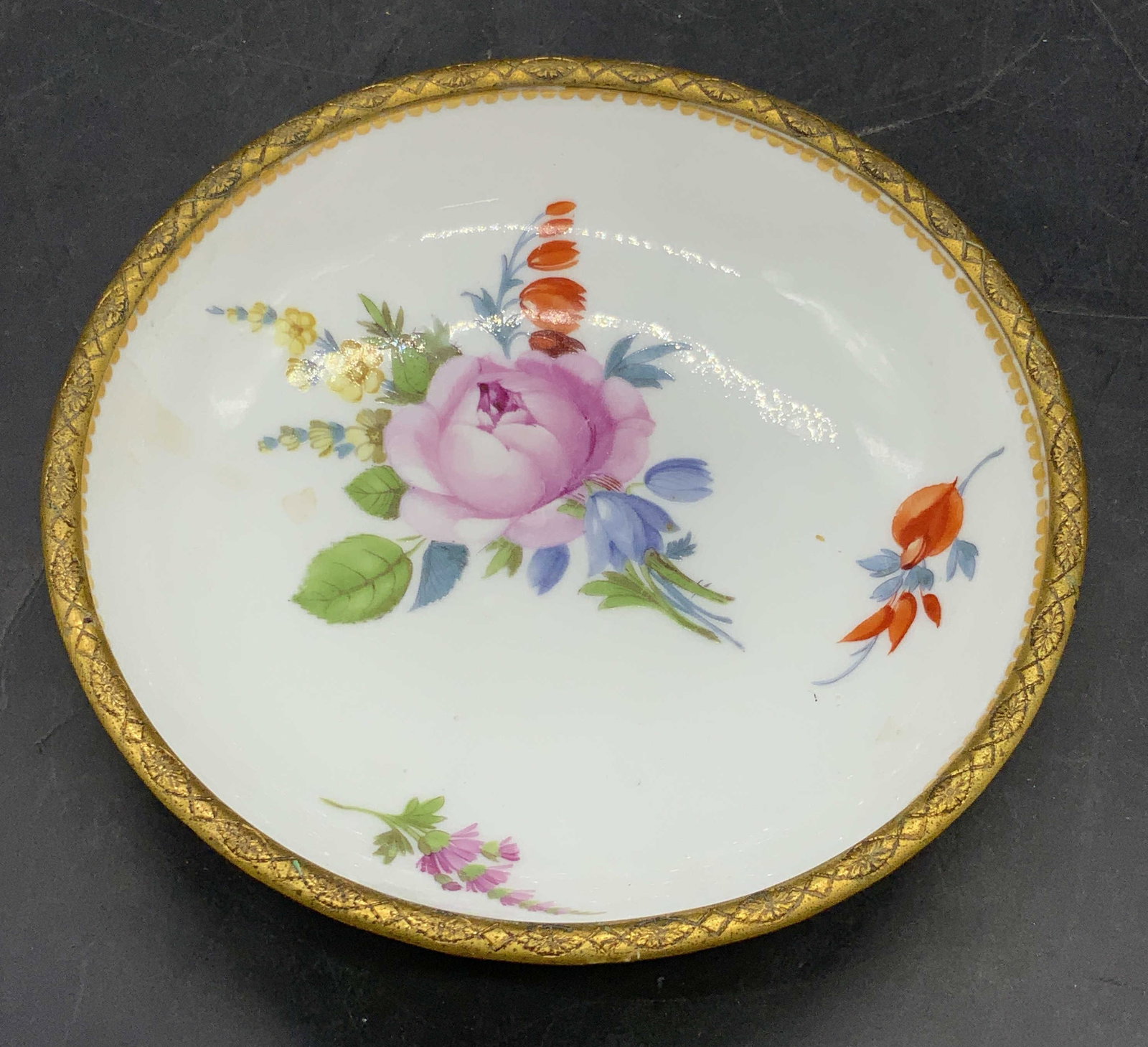 Vntg Trademarked Hand Painted Porcelain Floral Bowl: A vintage hand painted floral motif porcelain bowl with a brass hued metal rim. Underside trademarked with crossed swords and another symbol above. Possibly a Meissen trademark. Measures approx. 1.25H