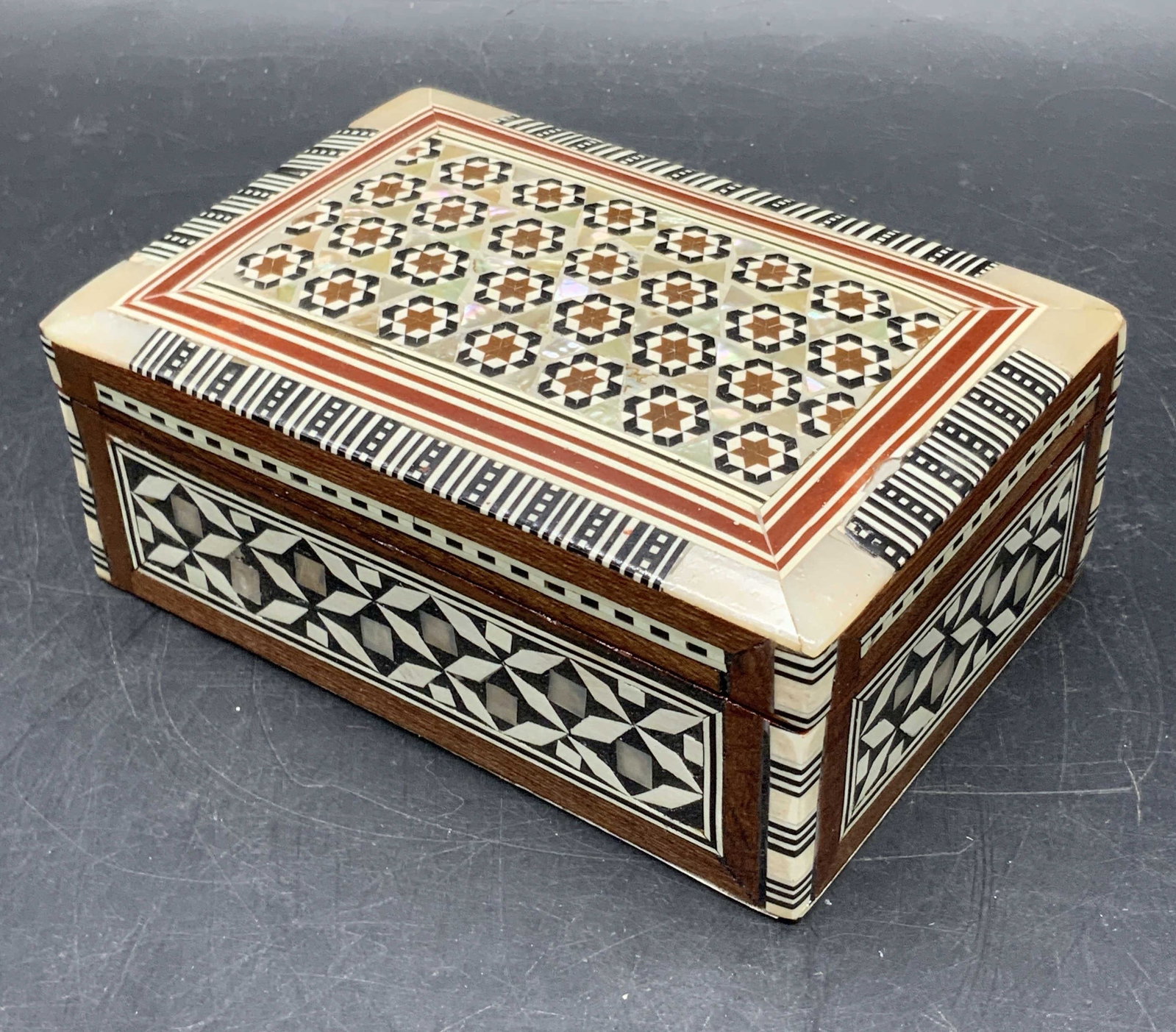 Inlaid Mother of Pearl Wooden Trinket Box: A wooden trinket box inlaid with mother of pearl. Measures approx. 2H x 5W in. Piece opens with hinge hardware. Some wear consistent with age, use, and exposure. Collectibles, woodwork, decorative art