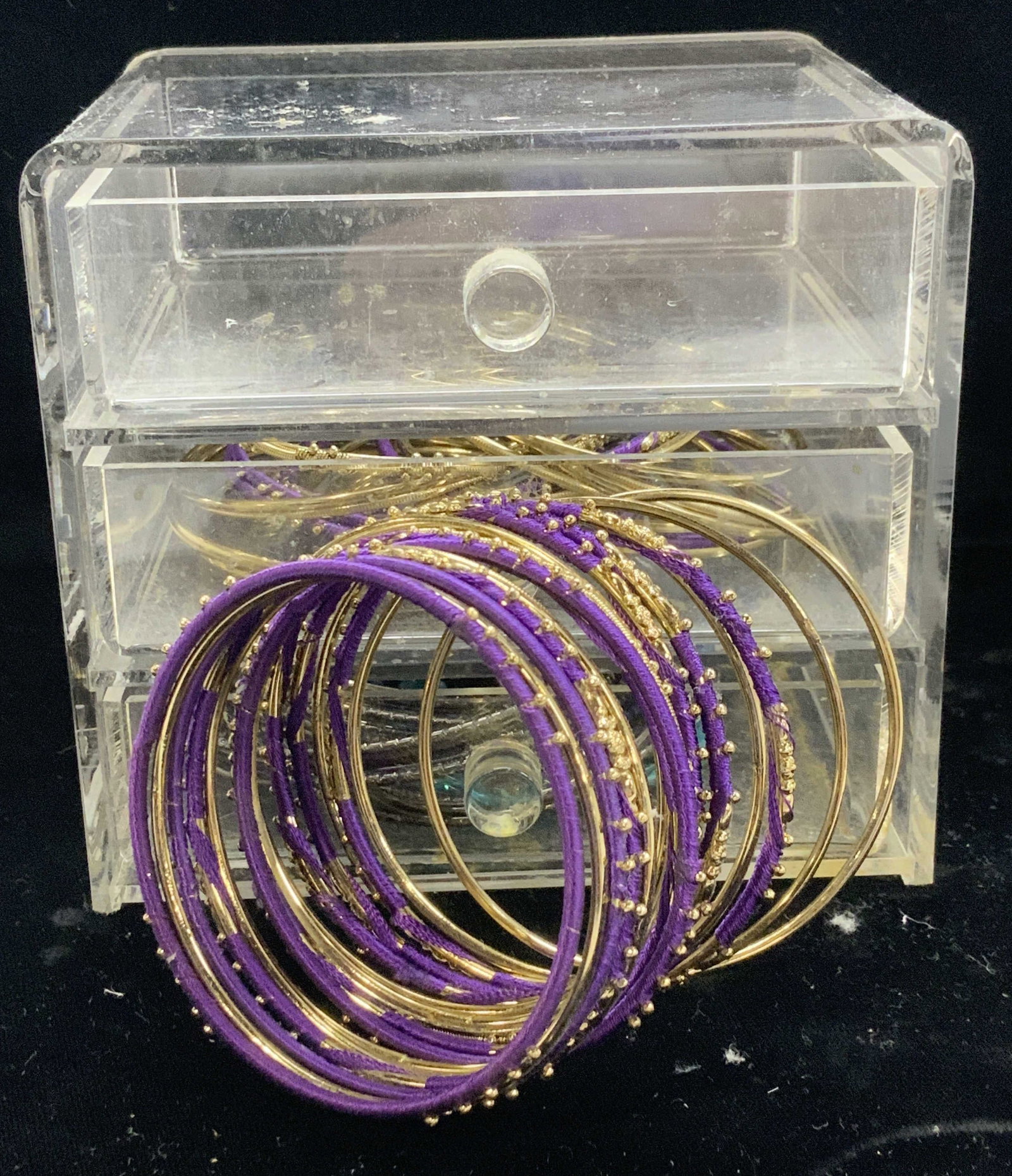 3 Drawer Acrylic Box w Stackable Bangles: 3 drawer clear acrylic box- for jewelry or other items with a variety of thin metal stackable bangles - gold tone, gun metal tone and wrapped purple strong over metal. Bad measures 4.5 in. Ht. X 5 in.