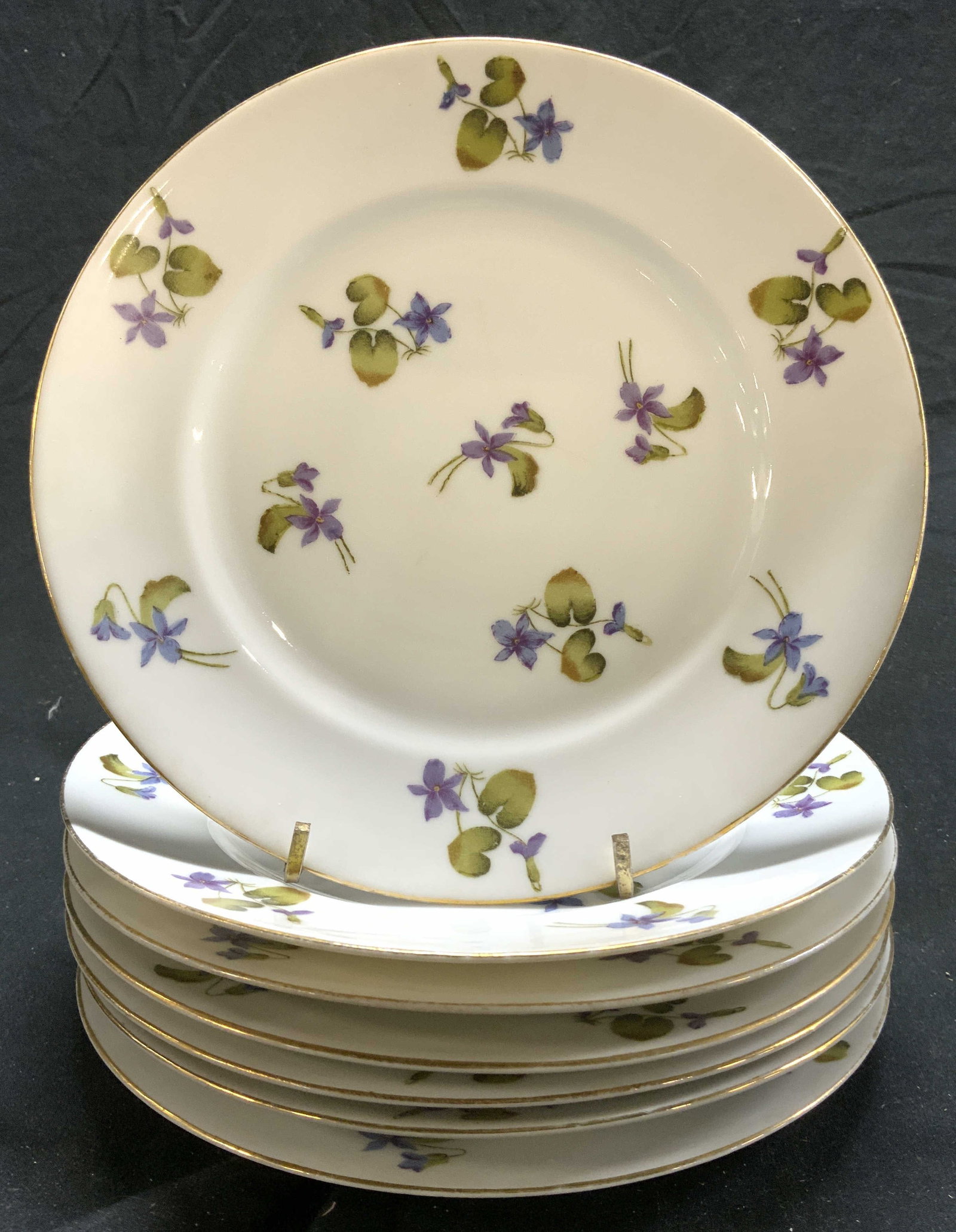 LS&S CARLSBAD Set 7 Porcelain Plates AUSTRIA: Undersides are marked LS&S CARLSBAD AUSTRIA. Lot includes 7 plates, each are white toned and porcelain with multi toned floral detail. Plates each have gilt rims. Each plate measures approx 7.75 inche