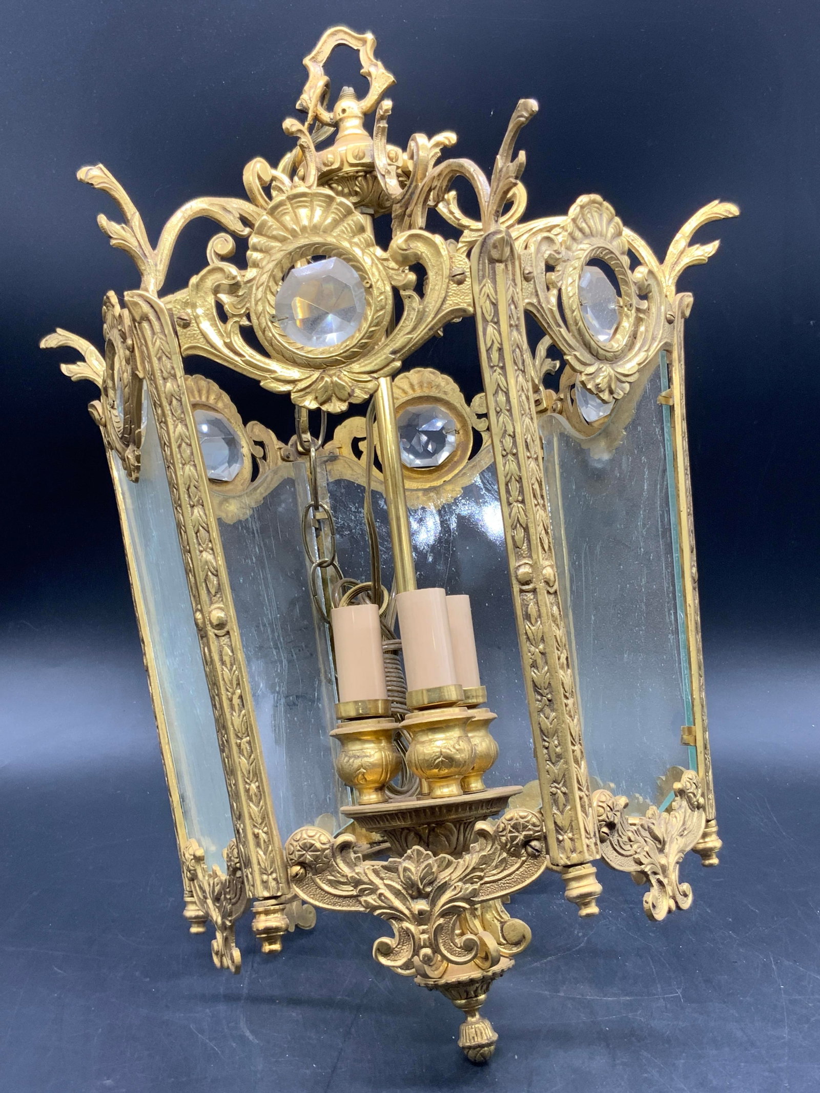 Vintage Gilded Metal Faceted Prism Chandelier: A vintage gilded metal chandelier featuring faceted colorless prisms. Three light. Glass panels to the sides. Swirls and bubbles to the glass. Weighty piece. Measures approx. 19.5L x 12W in. Not teste